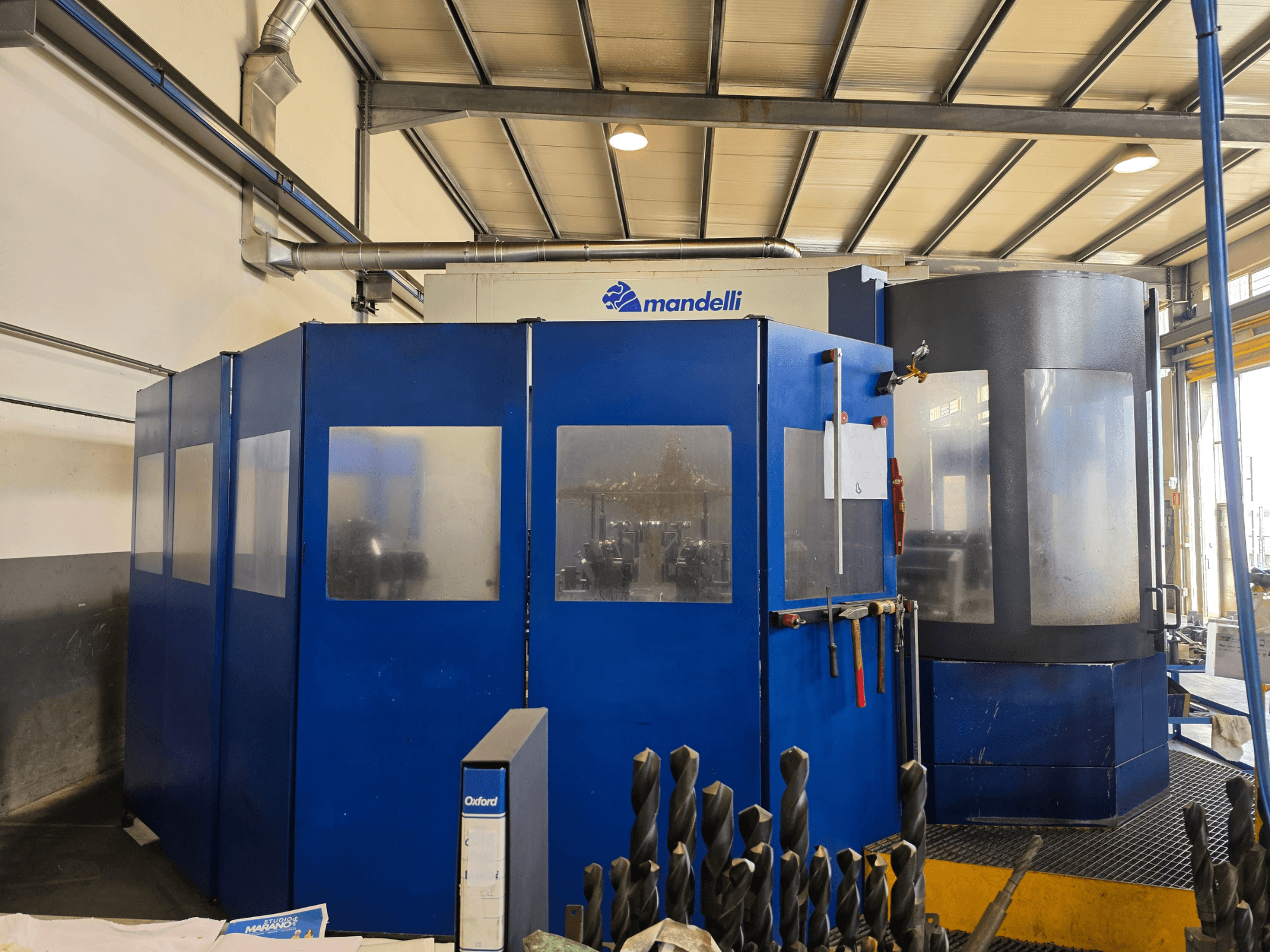 Mandelli STORM 1400 horizontālā apstrādes centra skats no priekšpuses, kurā redzams zils apvalks un piestiprinātie instrumenti.