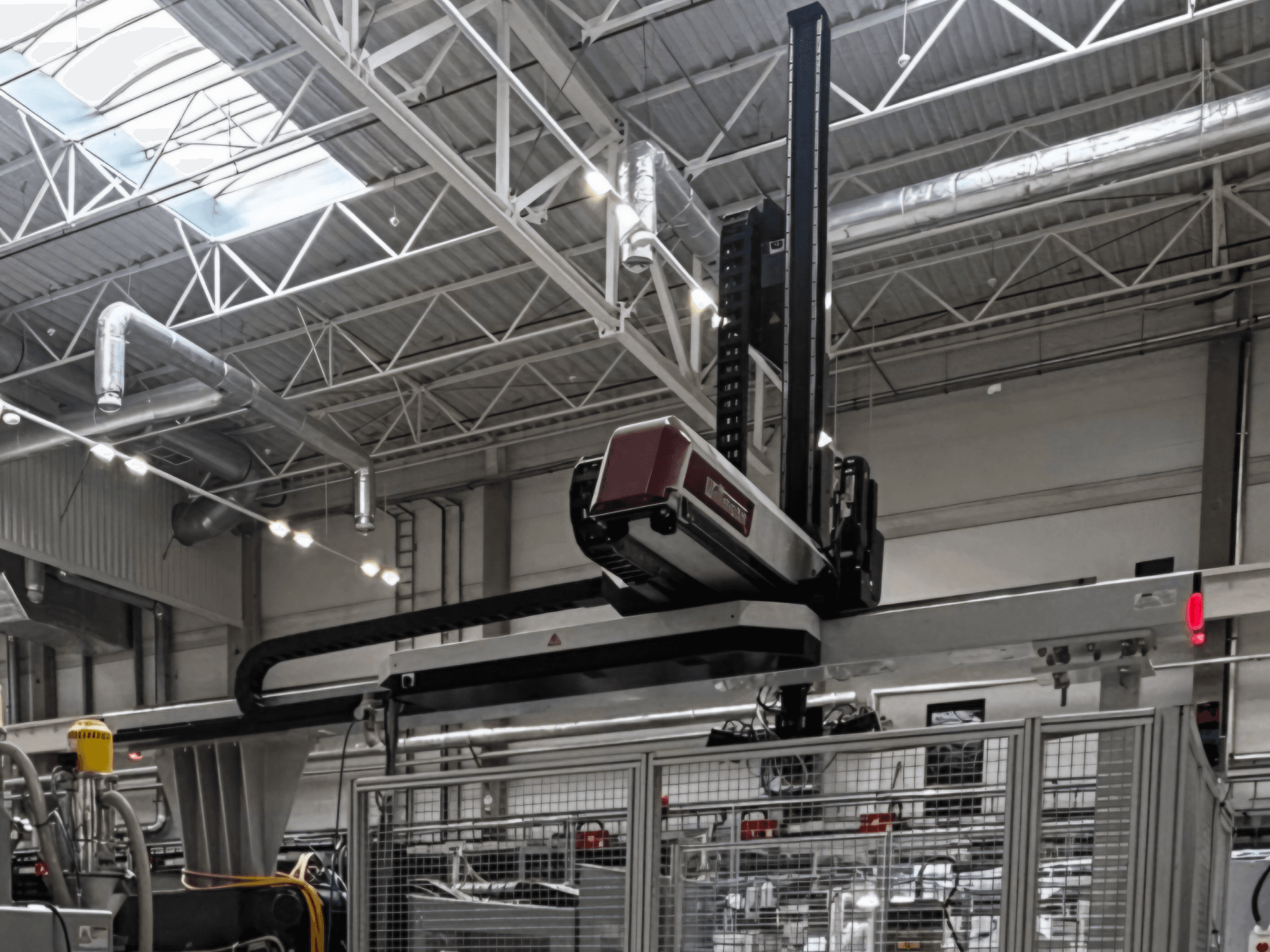 WITTMANN W832PRO plastmasas pārstrādes iekārta rūpnīcas vidē, sānskats, kurā redzama virsgalvas sistēma un rūpnieciskā vide.