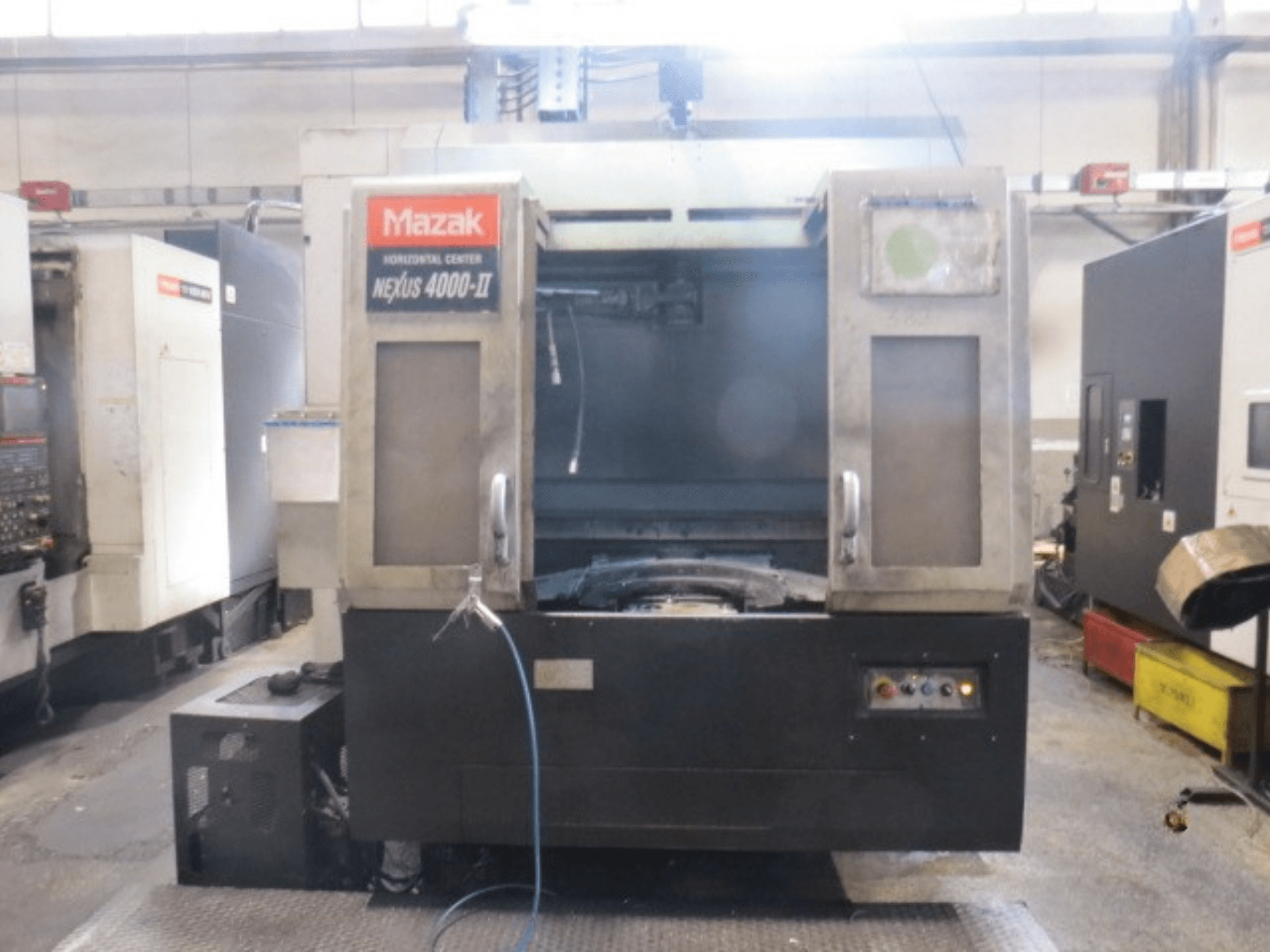 Mazak NEXUS 4000 II horizontālais apstrādes centrs, skats no priekšpuses, kurā redzams vadības panelis, dzesēšanas šķidruma padeve un atvērta darba zona.