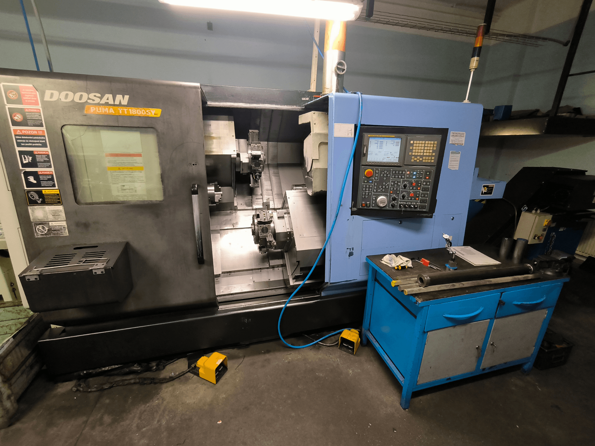 Doosan Puma TT1800SY CNC virpa, skats no priekšpuses, kurā redzams vadības panelis, darba zona ar instrumentiem un mašīnas sastāvdaļas.