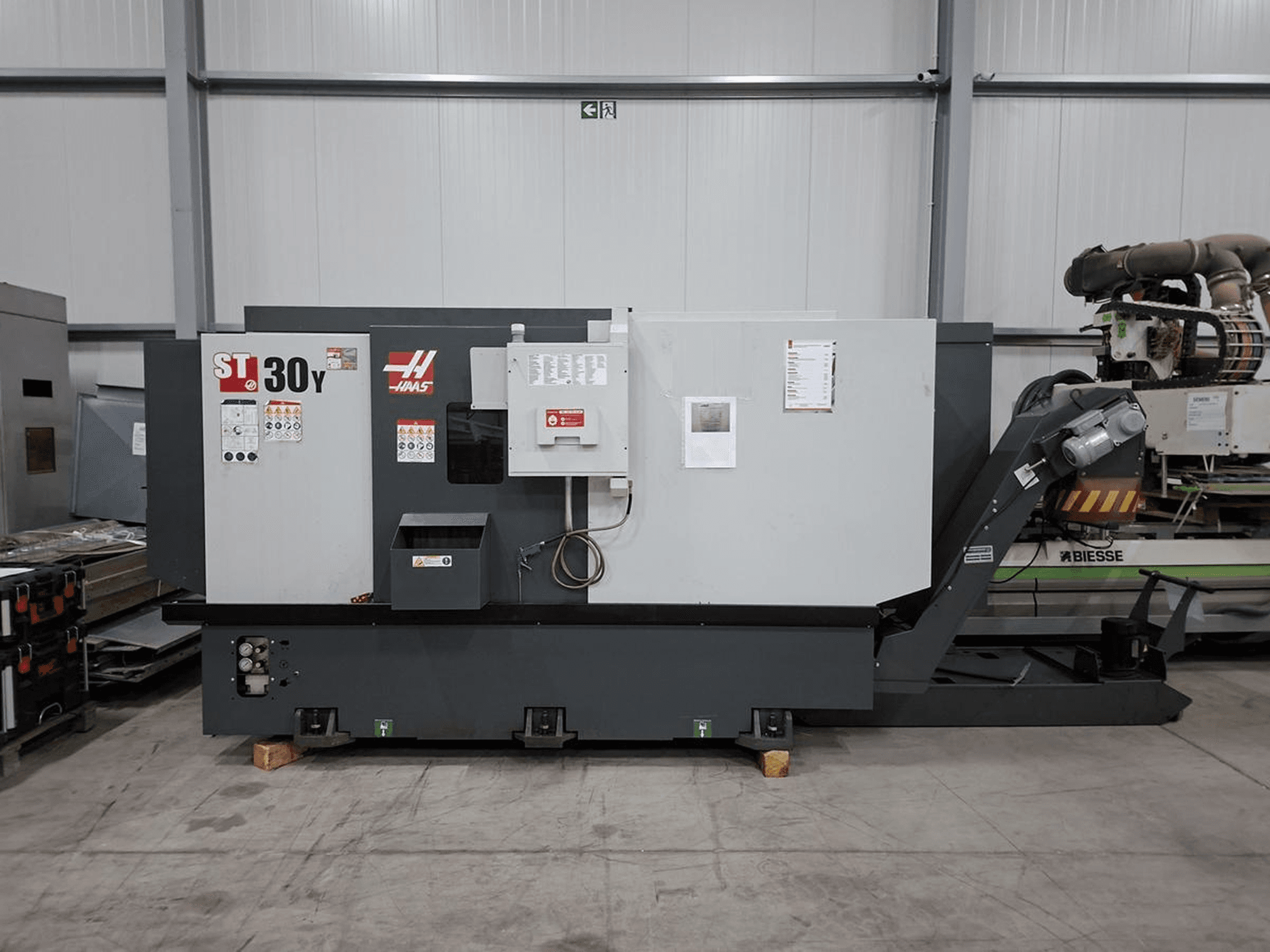 Haas ST-30Y horizontālā virpošanas mašīna no sāniem, kurā redzamas vadības ierīces, uzraksti un izturīgā konstrukcija plašā darbnīcā.