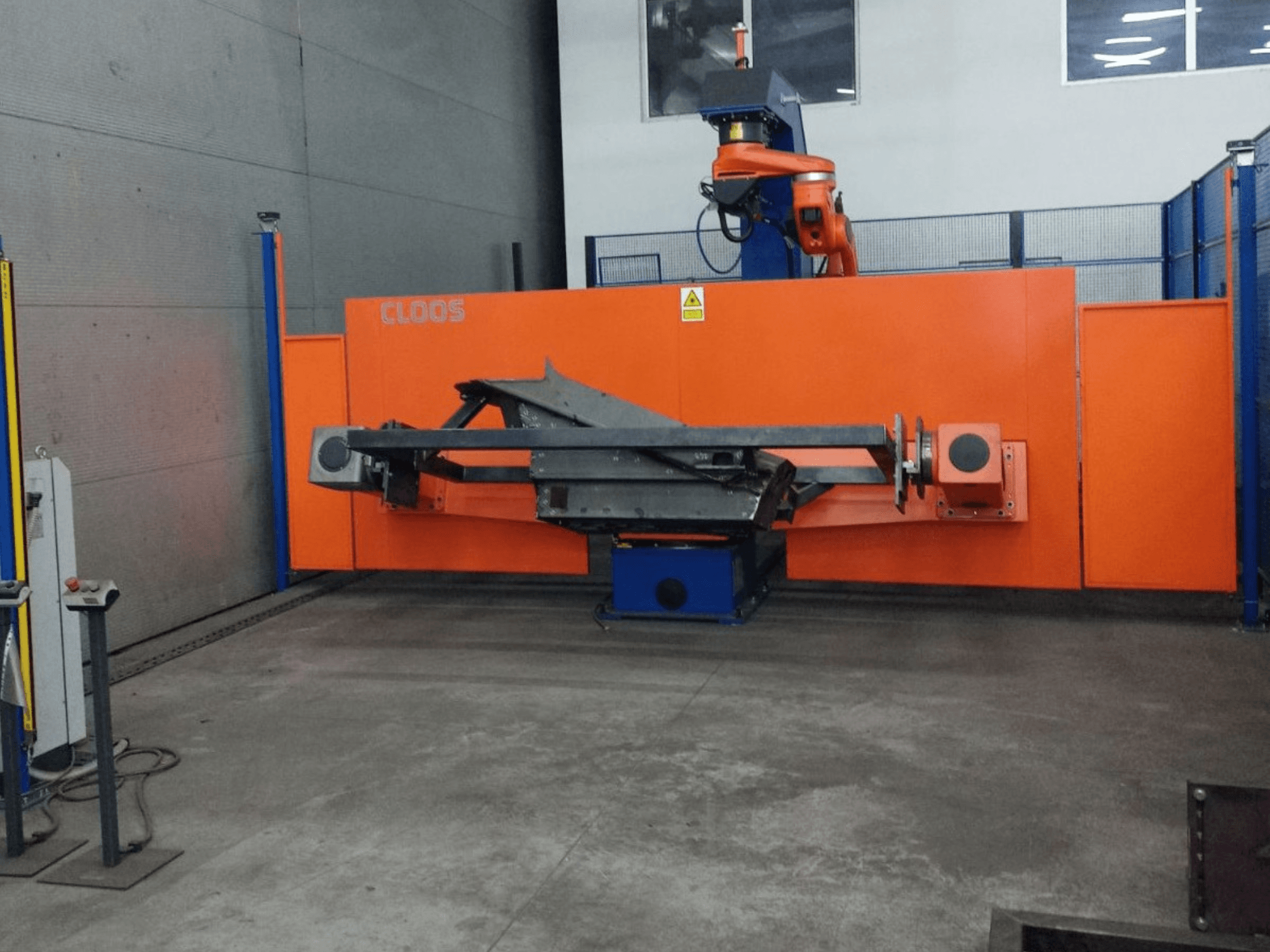 CLOOS QIROX QRC-350-E automatizācijas sistēmas ar robotizētu roku un metāla konstrukciju priekšējais skats industriālā vidē.