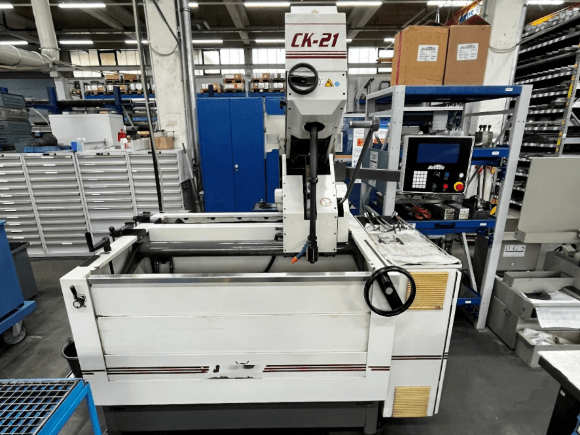 Sunnen CK-21-CC vertikālā honēšanas iekārta priekšpusē ar vadības ierīcēm, honēšanas zonu un palīgiekārtām fonā.