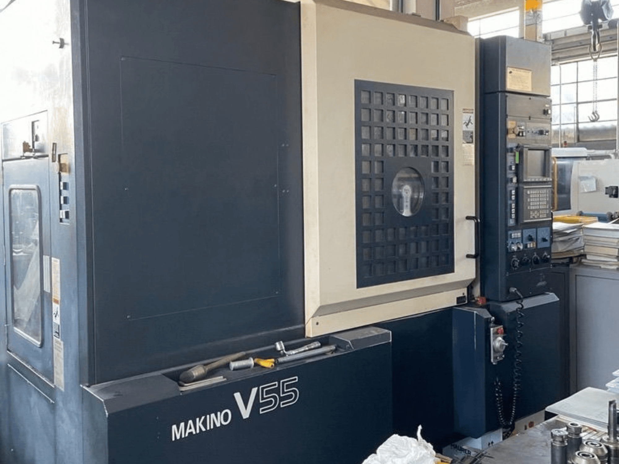 Vertikālais apstrādes centrs „Makino V55-A15“ — skats no priekšpuses, kurā redzams vadības panelis, izturīgā konstrukcija un darba zonas izkārtojums.