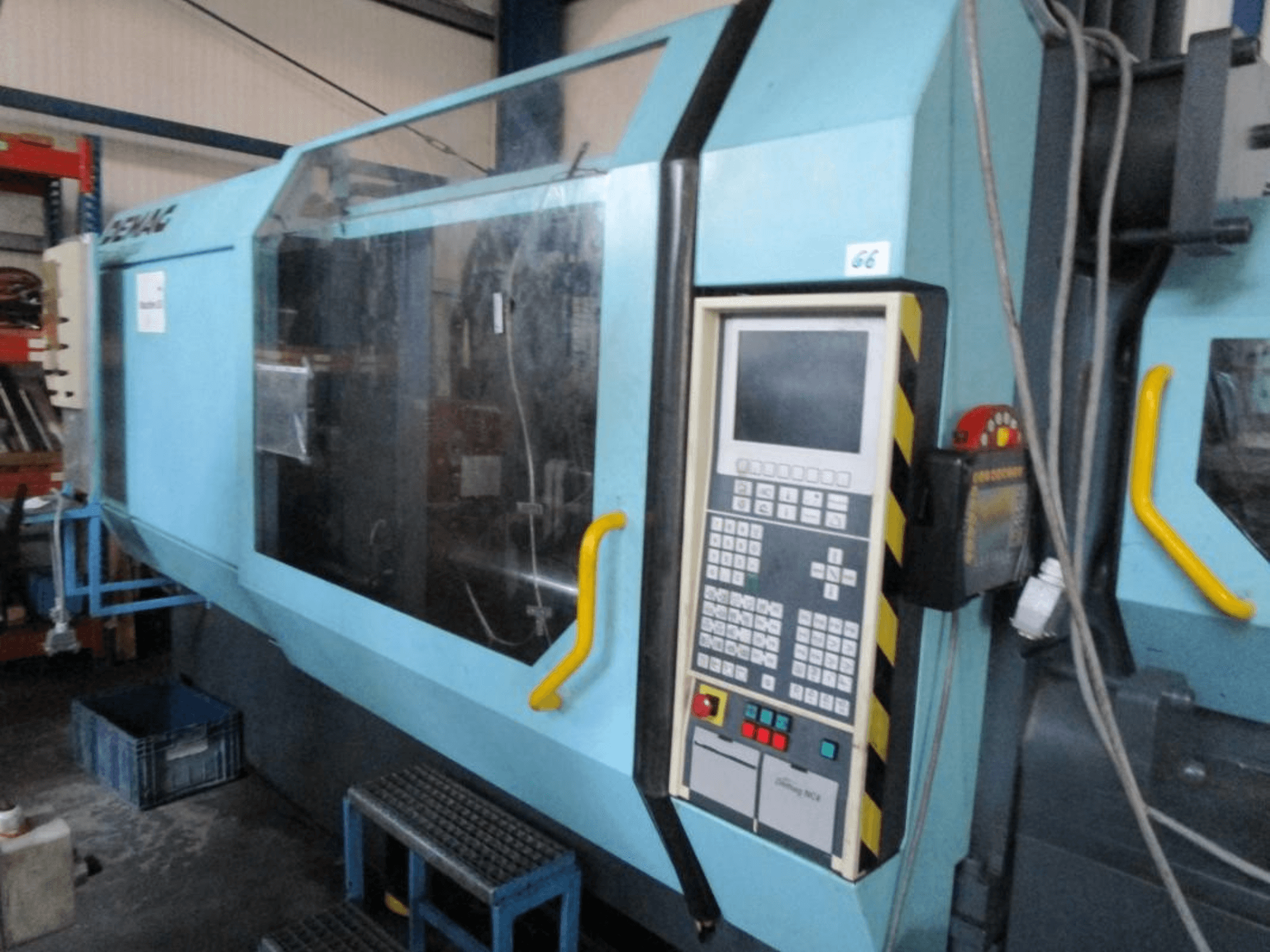 Demag Erdotech 500-3300 hidrauliskā iesmidzināšanas iekārta, skats no priekšpuses, vadības panelis un caurspīdīgs drošības korpuss.