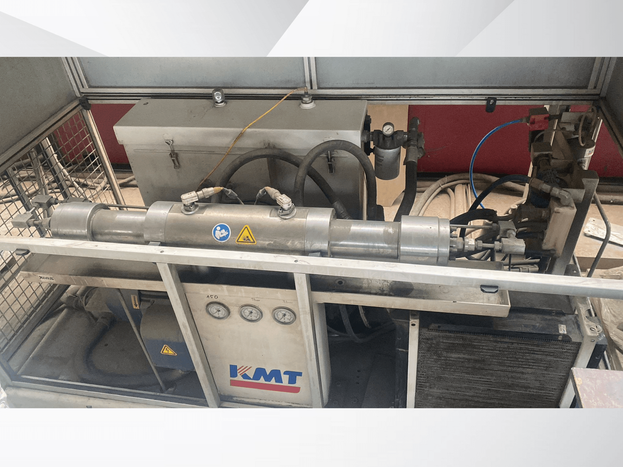KMT hidrauliskā iekārta priekšpusē, ar manometriem, šļūtenēm un metāla korpusu, ideāli piemērota rūpnieciskiem lietojumiem.