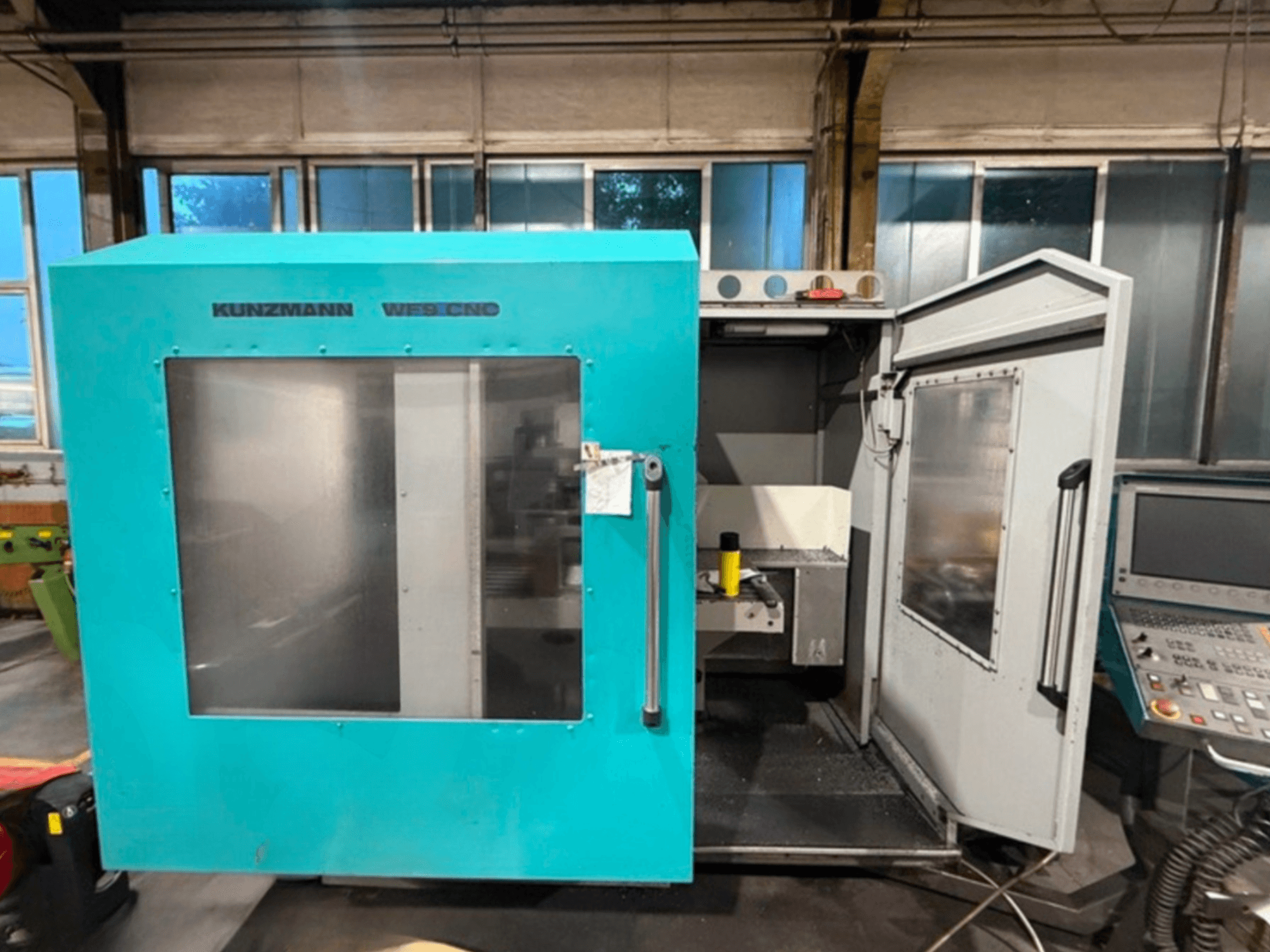 KUNZMANN WF9 CNC vertikālais apstrādes centrs, skats no priekšpuses ar atvērtām durvīm, kurā redzams iekšpuse un vadības panelis.