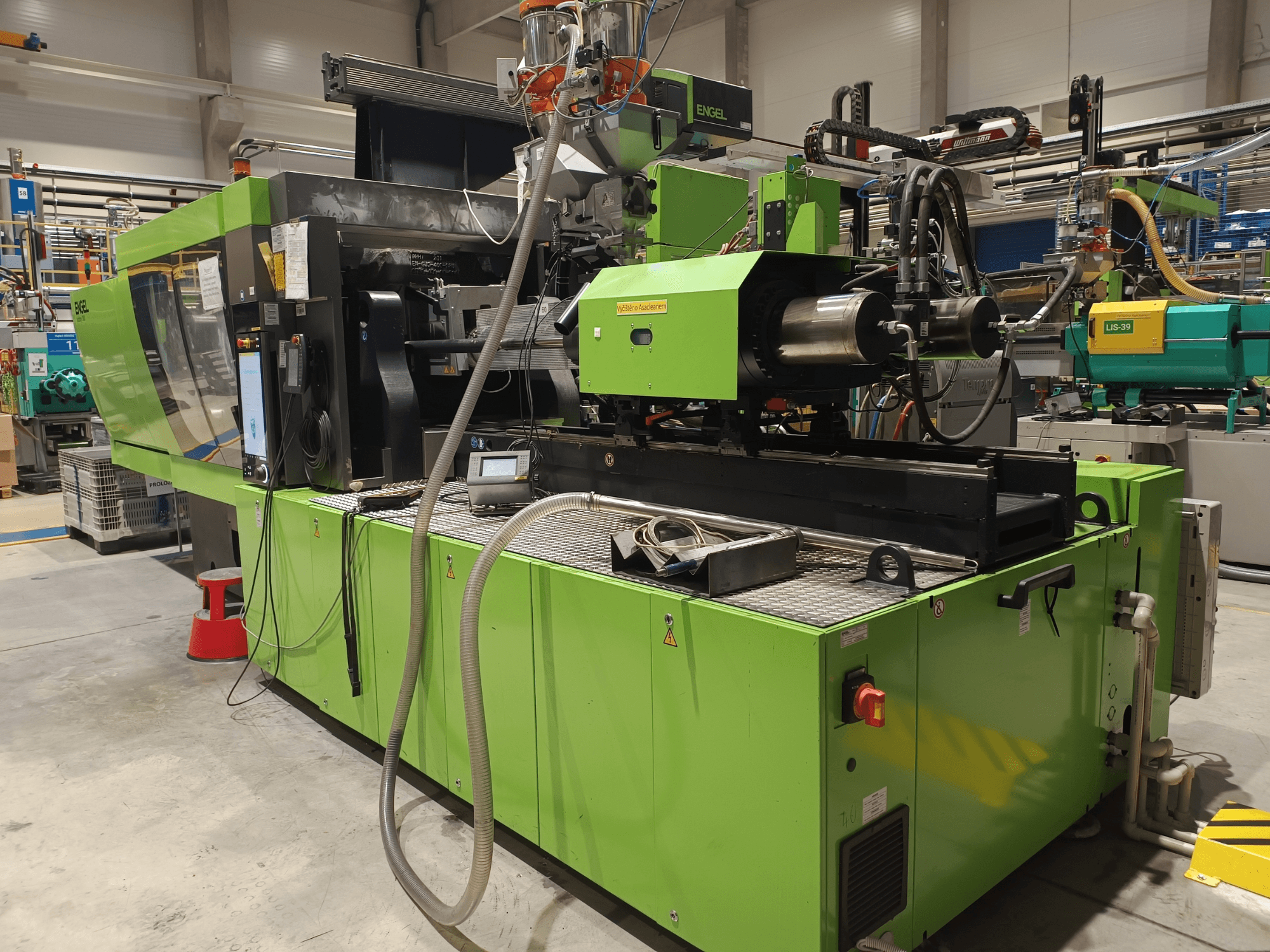 Engel iesmidzināšanas veidošanas iekārta, skats no sāniem, zaļa ārējā apdare, redzams skārienjūtīgā ekrāna panelis un hidrauliskie komponenti.