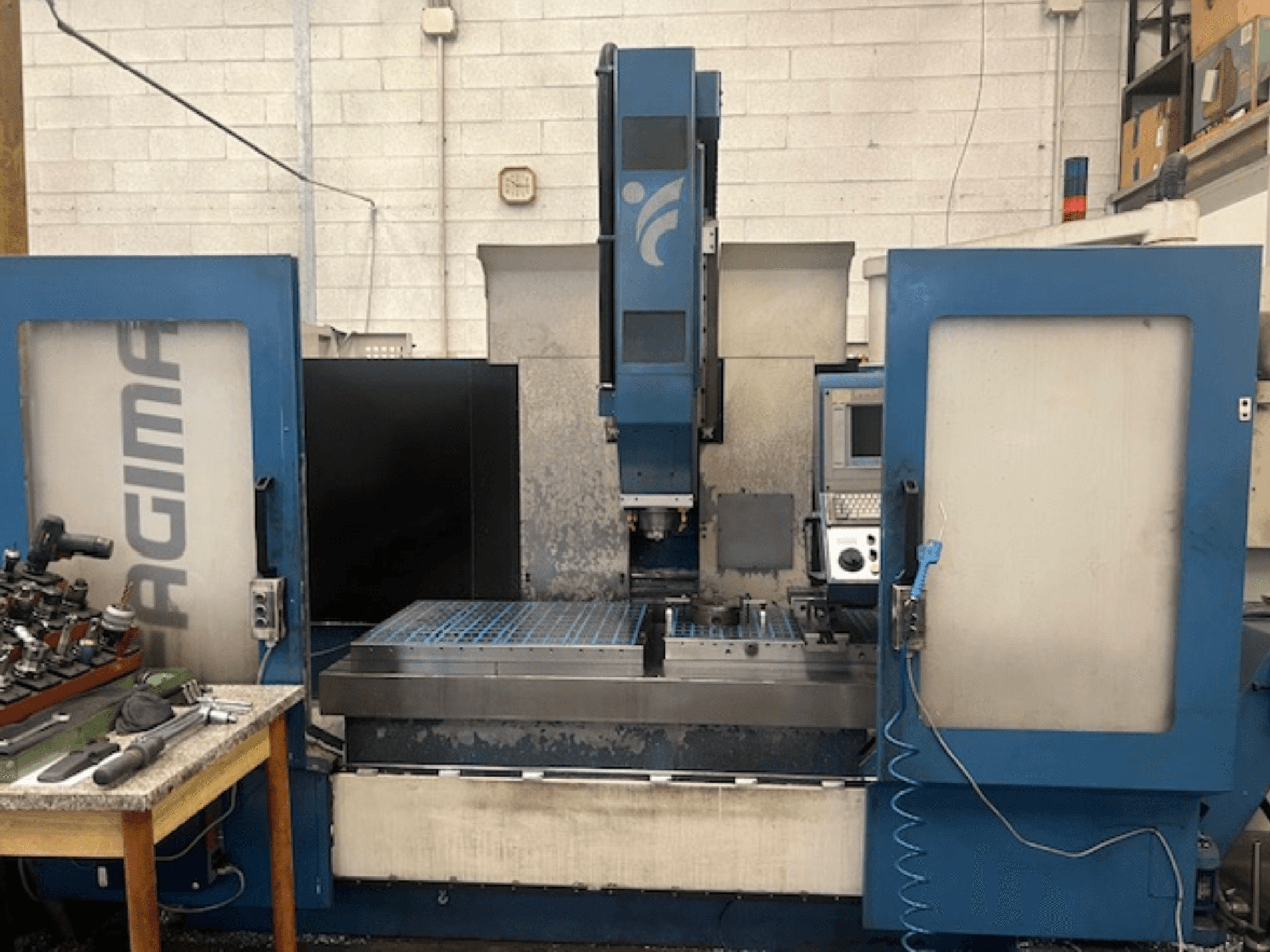 Skats no priekšpuses uz JAGIMA CNC darbgaldu ar lielu metāla darba vietu, redzamu vadības paneli un instrumentiem uz blakus esošā galda.