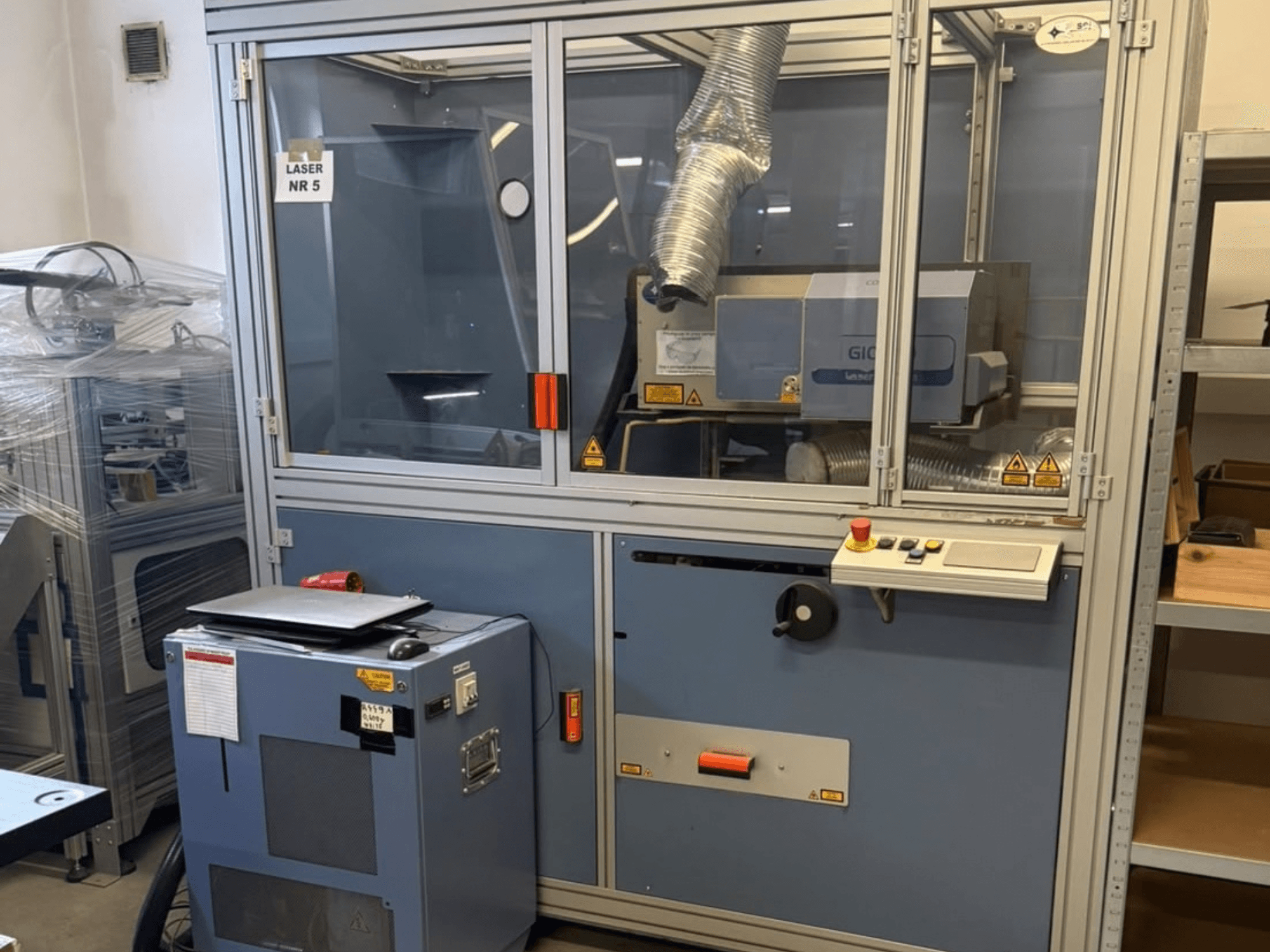 CO₂ lāzergriešanas iekārta „SEI Laser PAPER BLASTER 02“, skats no priekšpuses; redzams vadības panelis un izplūdes kanāls.