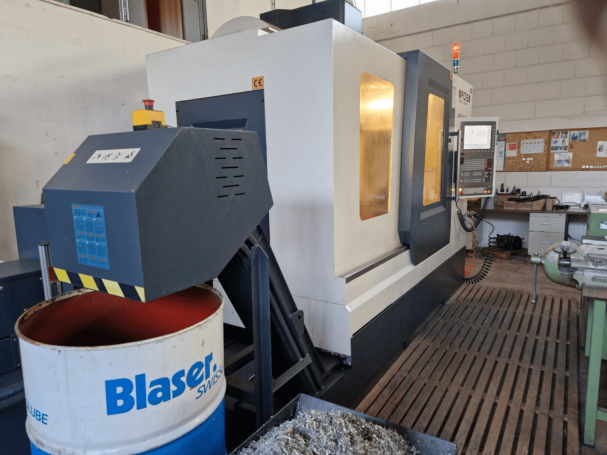 POSmill C 1050 vertikālā apstrādes centra priekšējais skats, redzama dzesēšanas sistēma virs Blaser cilindra un vadības panelis.