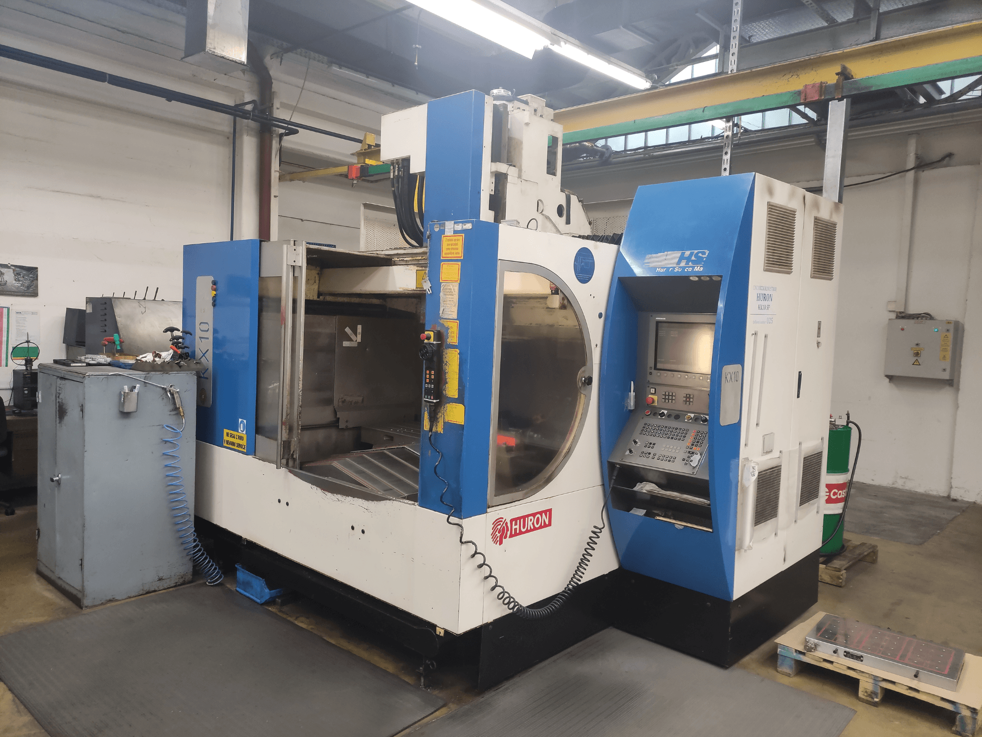 HURON KX10 CNC darbnīcā, skats no priekšpuses, ar vadības paneli un lielu atvērumu apstrādei.