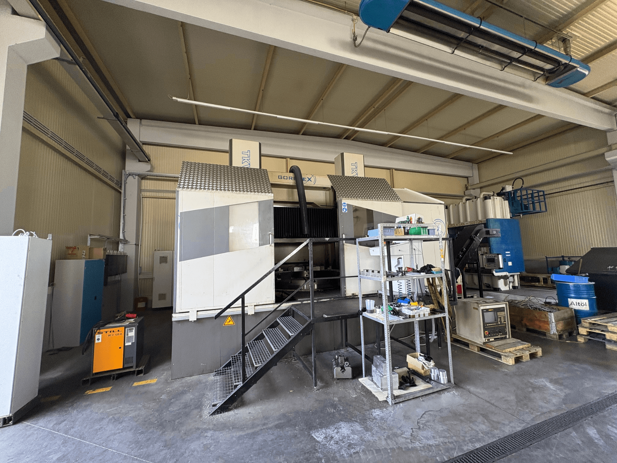 Rūpnieciskās apstrādes iekārta ar GORAT X mašīnu, skats no sāniem; ietver instrumentus, vadības paneli un iekārtas uz plauktiem.