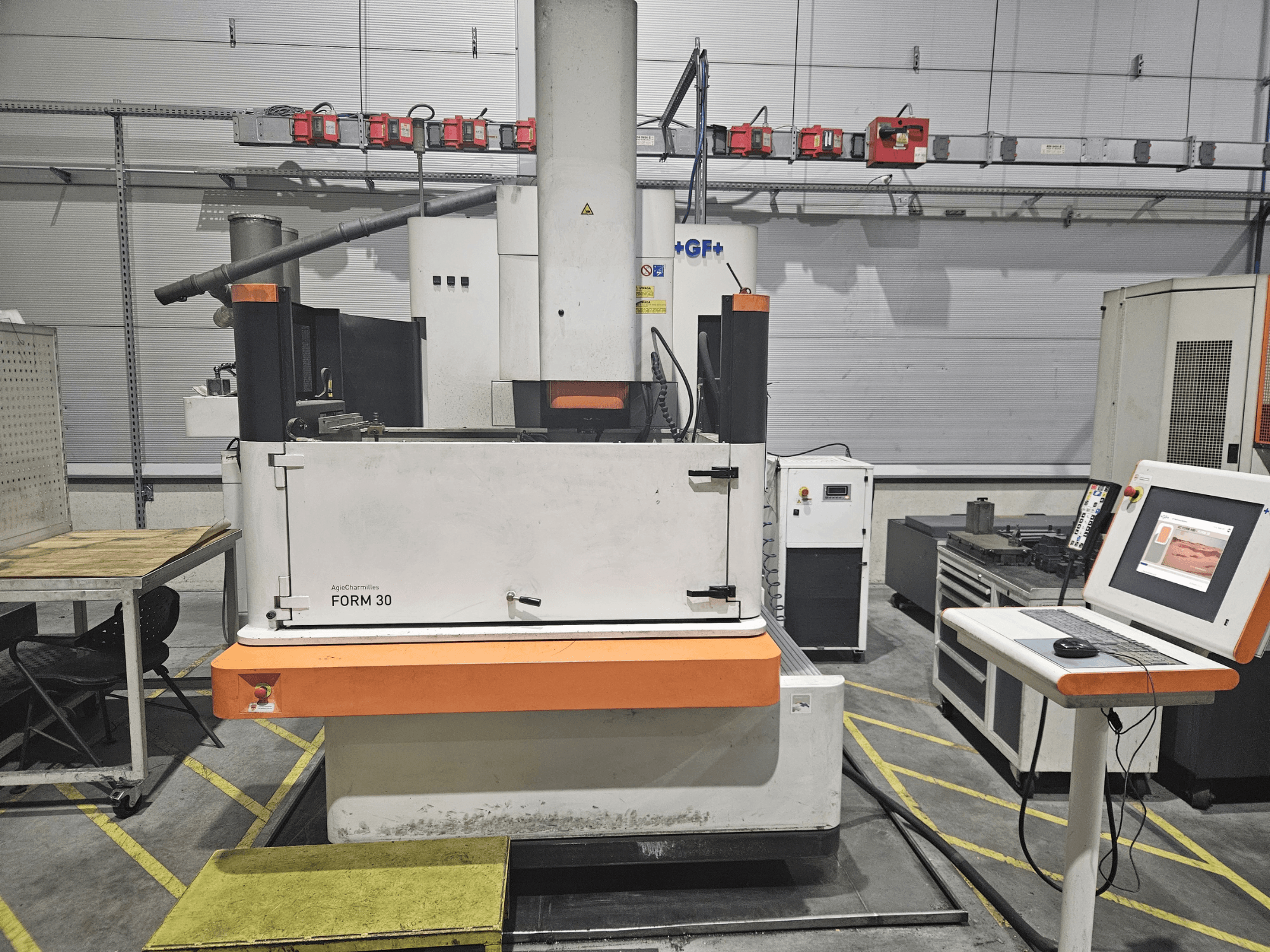 ApeqChemicals FORM 30 mašīna darbnīcā, skats no priekšpuses ar vadības paneli un darba galdu sānos.