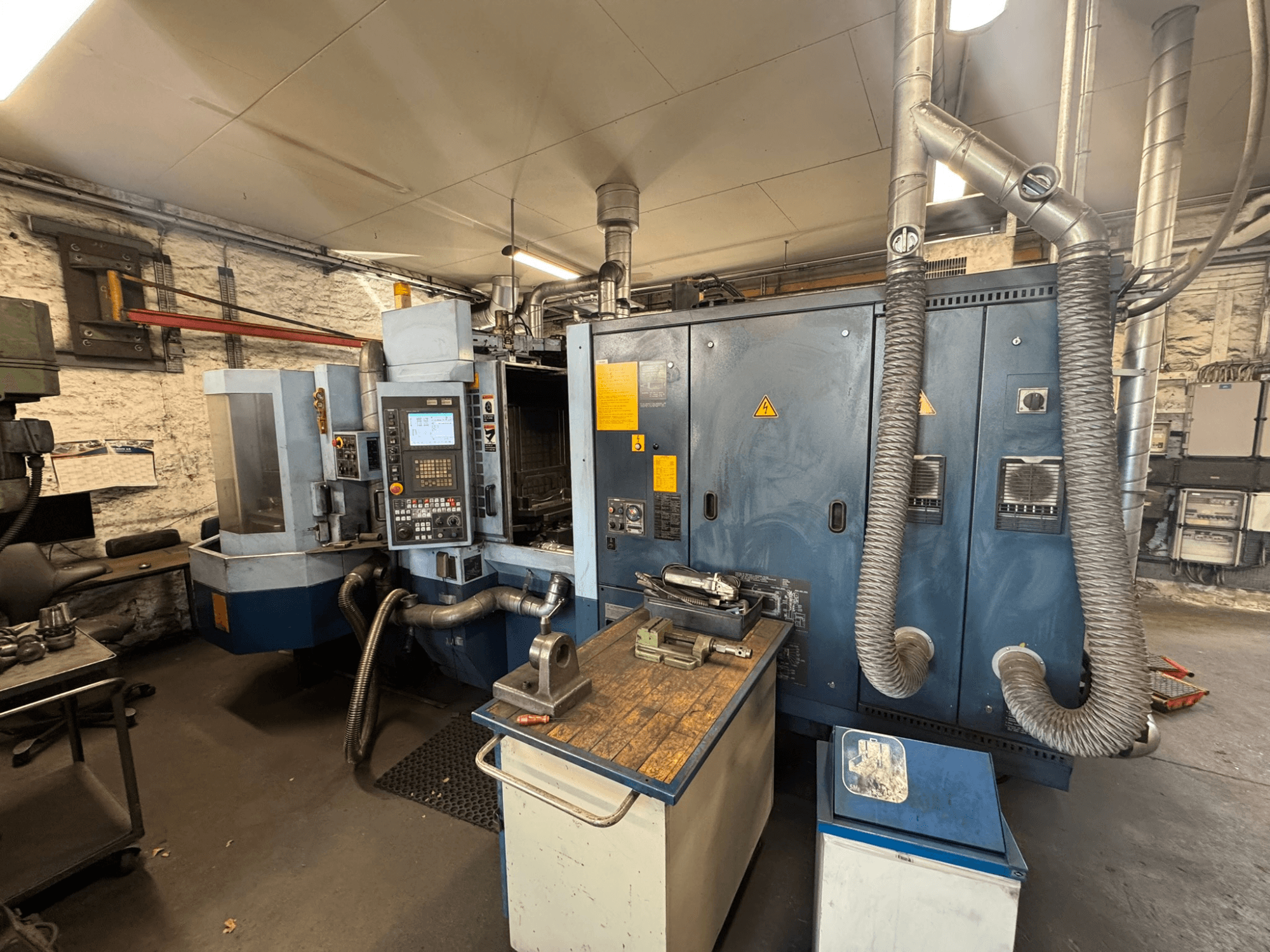 Matsuura H.PLUS-300 horizontālais apstrādes centrs darbnīcā, skats no priekšpuses, kurā redzams vadības panelis un darba galds.