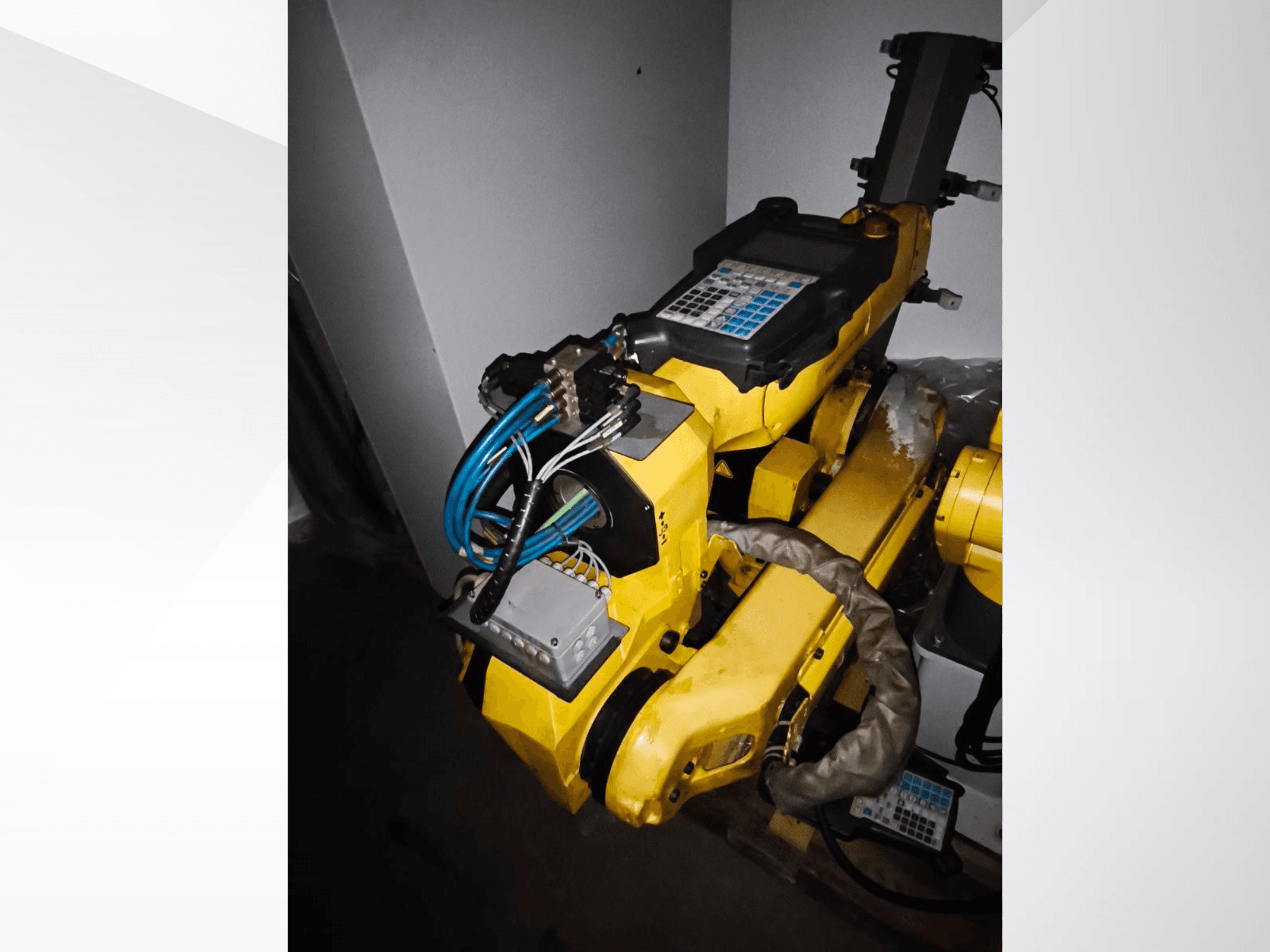 FANUC M-20iA robota rokas sānu skats, kurā redzams dzeltenais korpuss, vadības panelis un savienotie vadi.