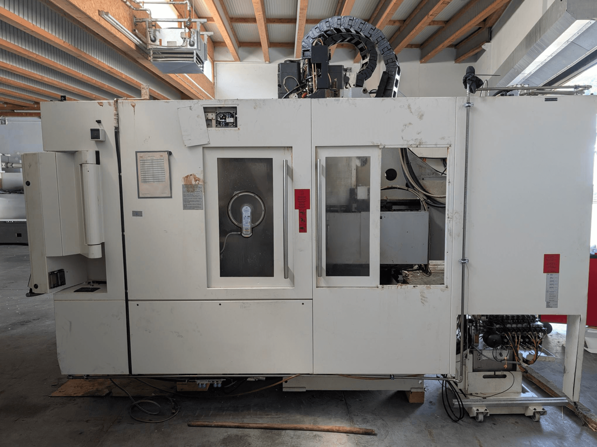 STAMA MC 326 vertikālais apstrādes centrs, sānu skats, kurā redzams vadības panelis, vārpstas zona un dažādas uz mašīnas esošās etiķetes.