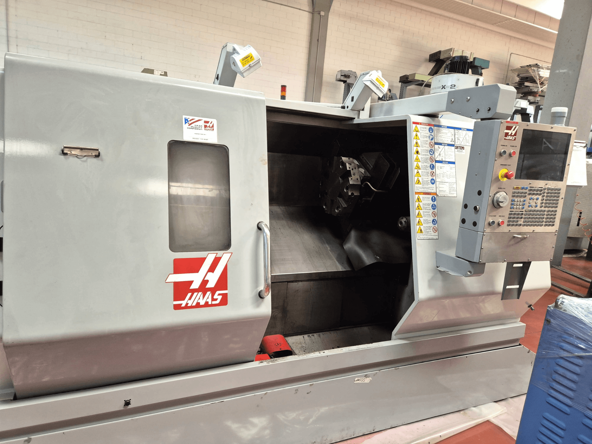 Haas SL 30TBHE horizontālā virpošanas mašīna, skats no priekšpuses, kurā redzamas vadības ierīces un atvērts nodalījums apstrādes darbībām.