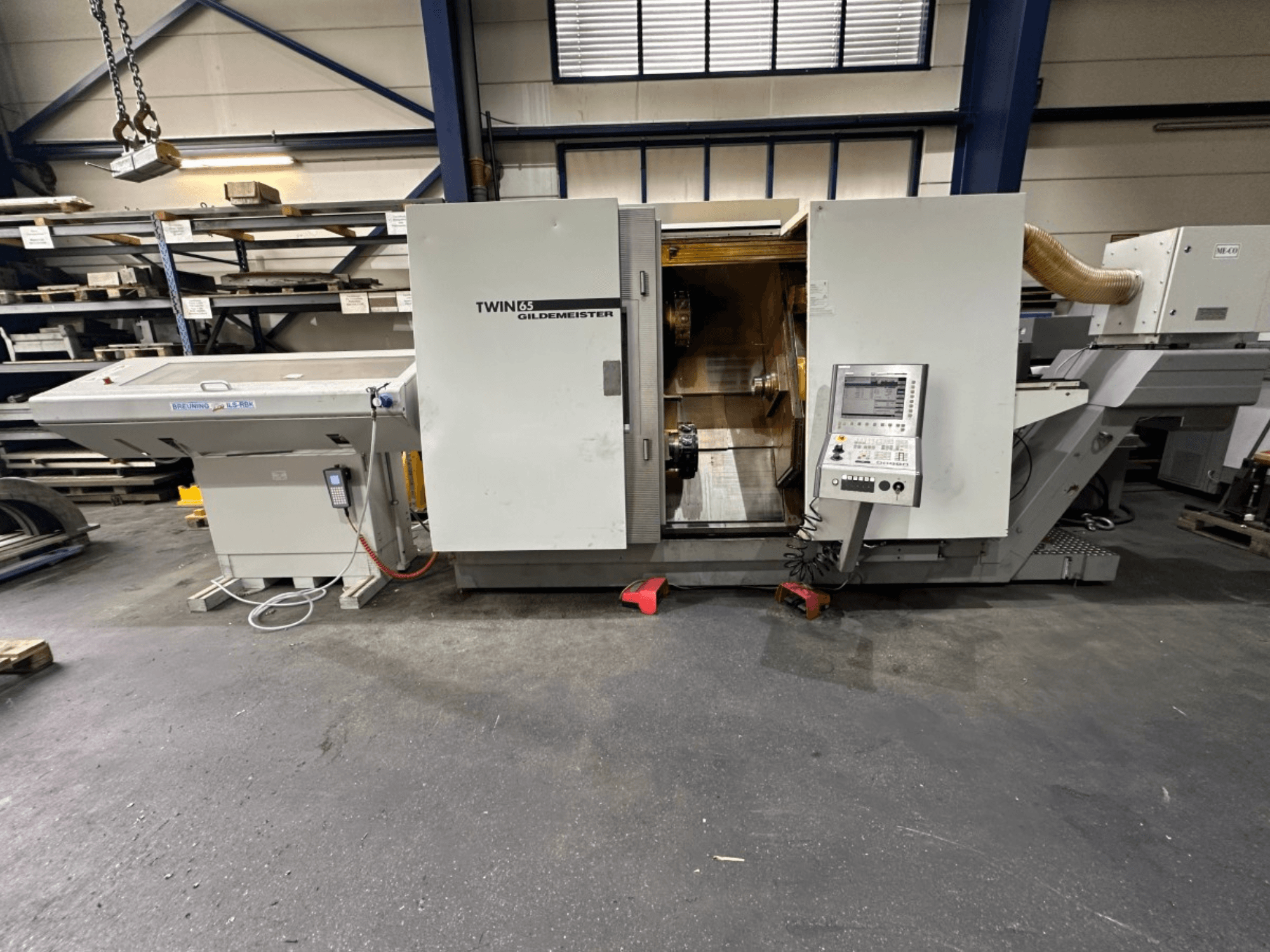 Gildemeister TWIN 65 horizontālās virpošanas darbgalds, skats no priekšpuses; vadības panelis un redzams detaļu apstrādei paredzētais iekšējais apdares elements.