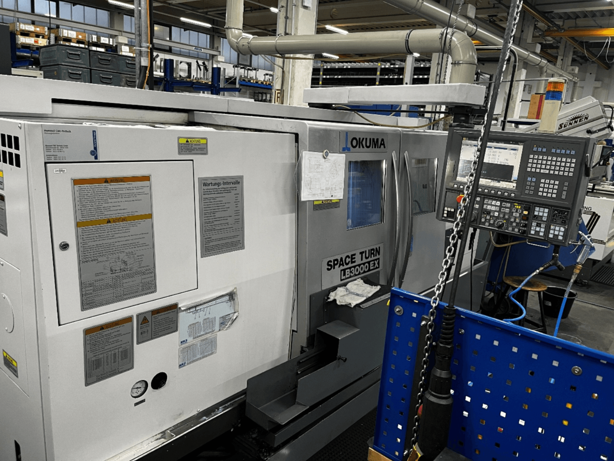 Okuma LB3000 EX horizontālās virpošanas iekārta, skats no priekšpuses, sānos redzams vadības panelis un drošības informācija.