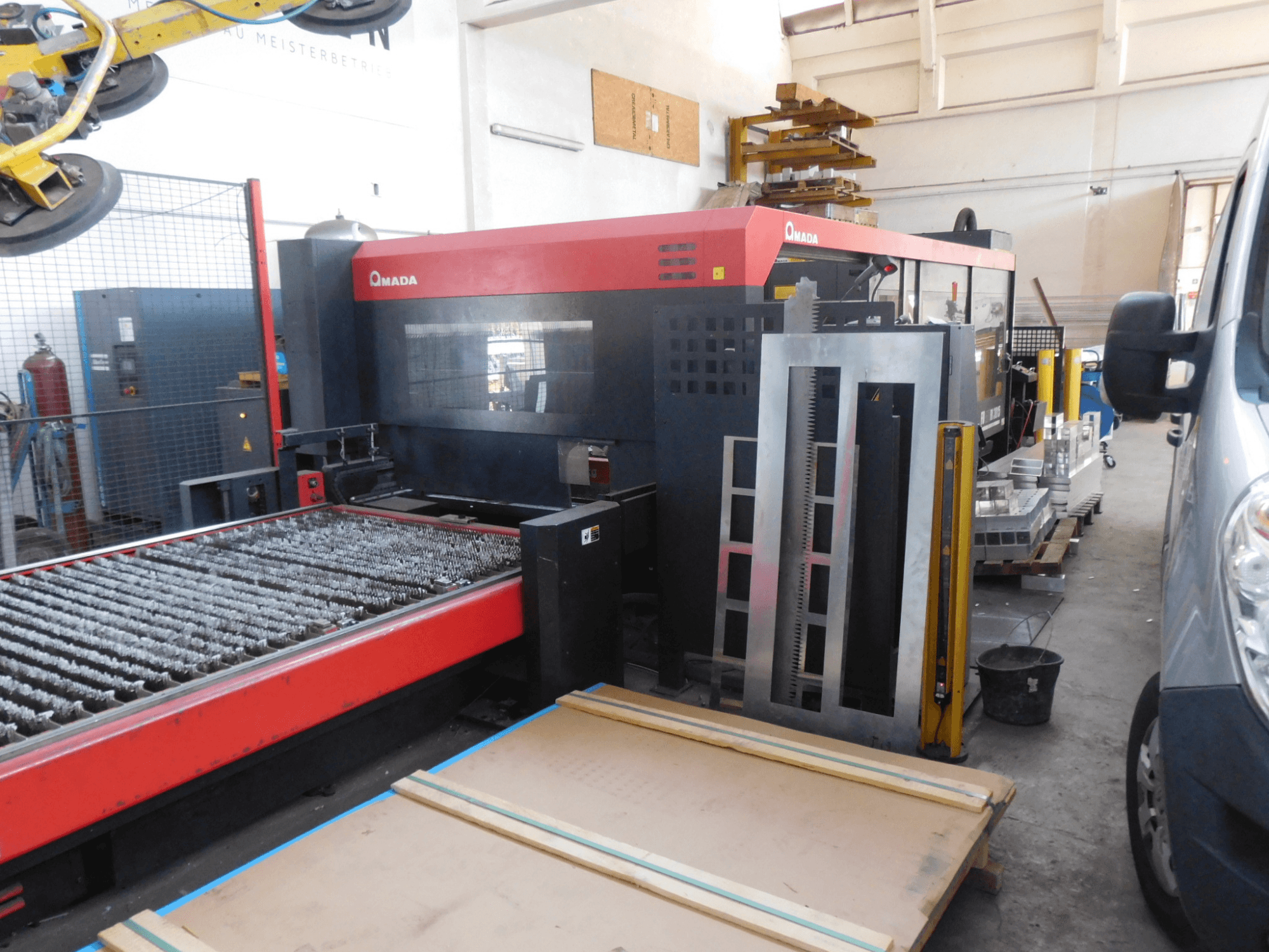 AMADA FO-3015 II RI CO2 lāzergriešanas iekārtas priekšējais skats ar griešanas gultni un apkārtējo darba zonu.