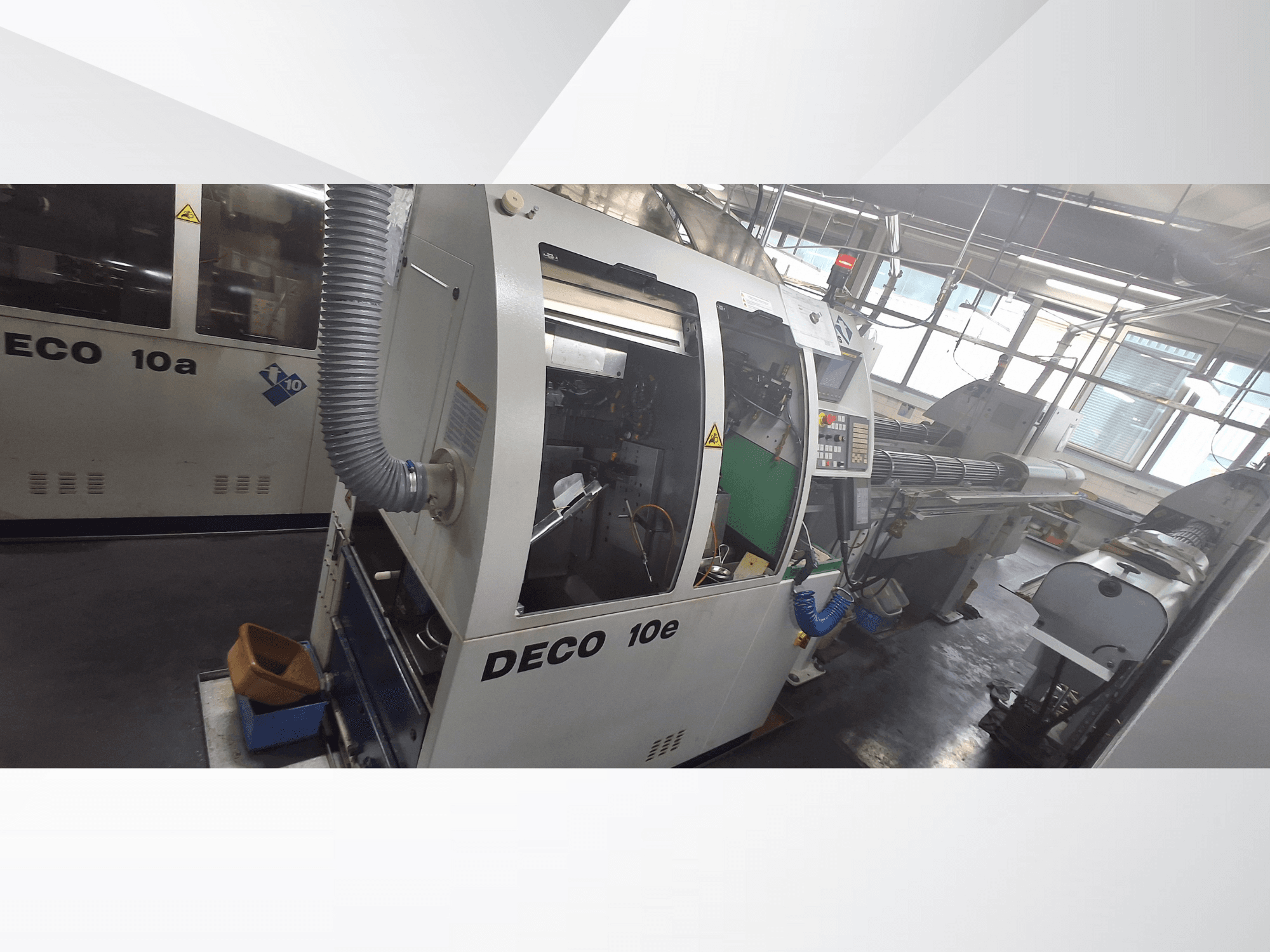 DECO 10e CNC mašīna no sānu skata, ar vadības paneli, zaļu iekšpusi un pievienoto izplūdes šļūteni.