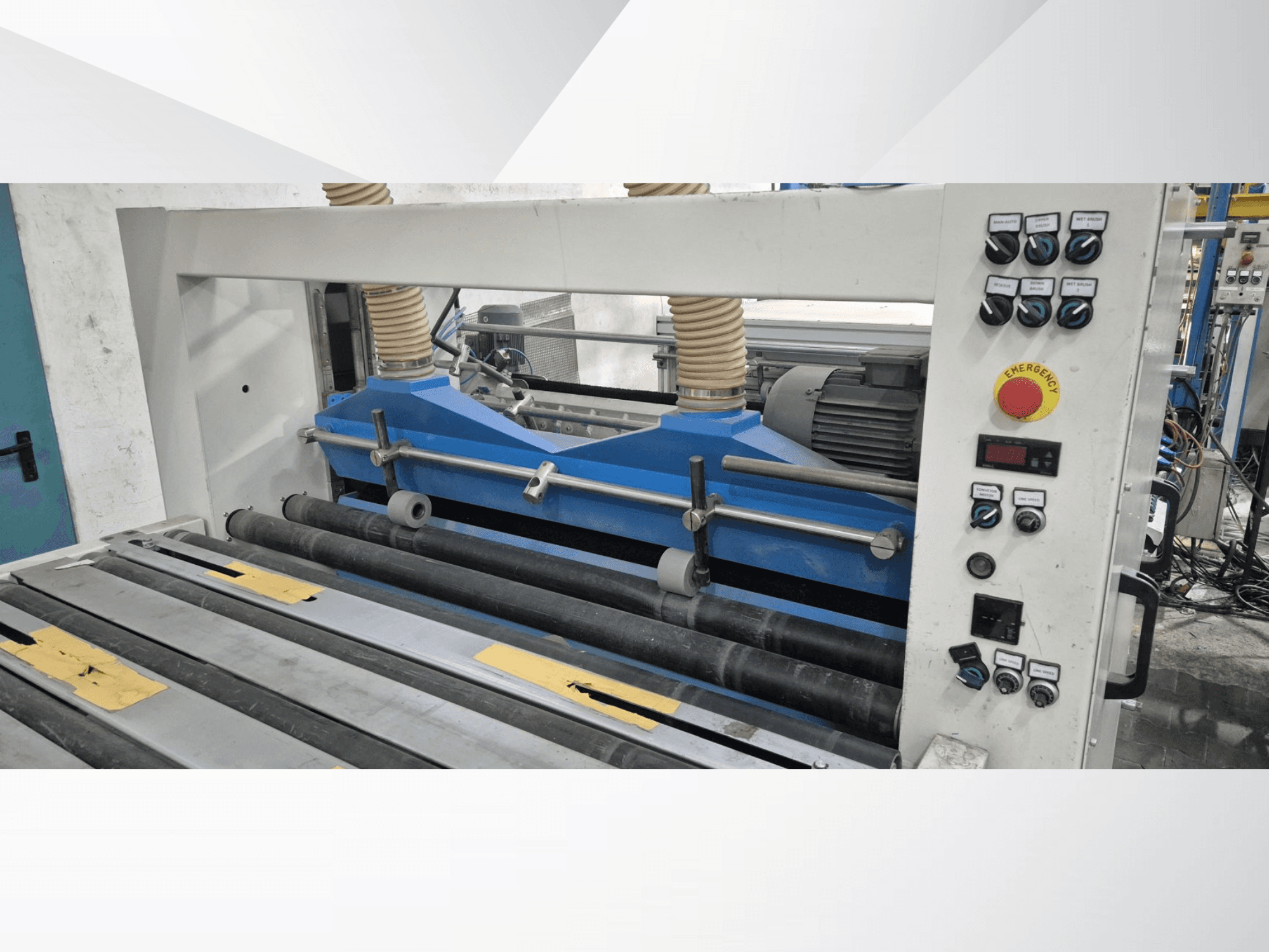 Rūpnieciskā ritošā mašīna ar ziliem komponentiem, skats no priekšpuses, ar vadības paneli un avārijas apturēšanas pogu.