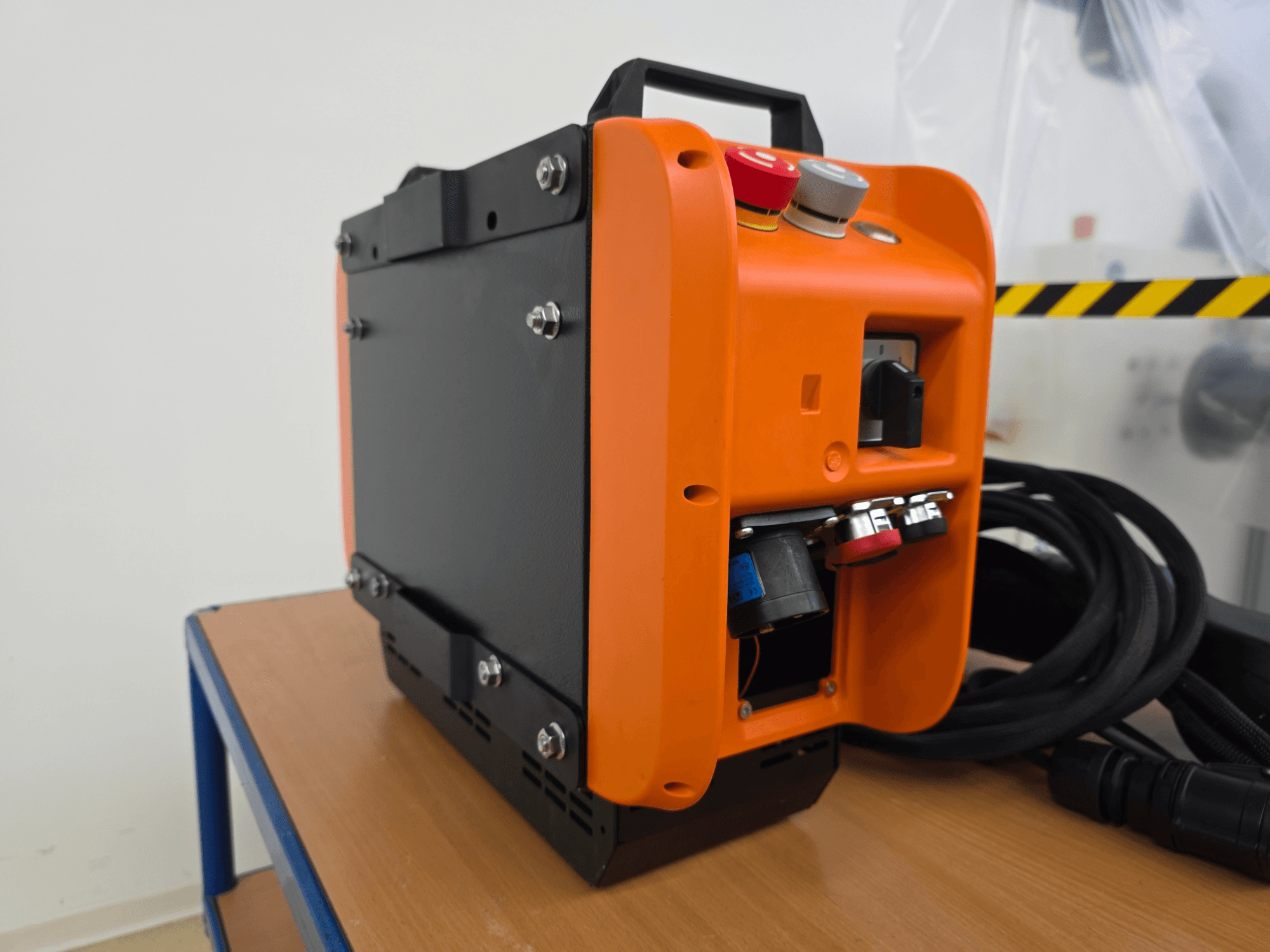 KASSOW ROBOTS KR1205 robota rokas kontrolieris, sānu skats, kurā redzams oranžs un melns dizains, ieejas/izejas porti un kabeļi.