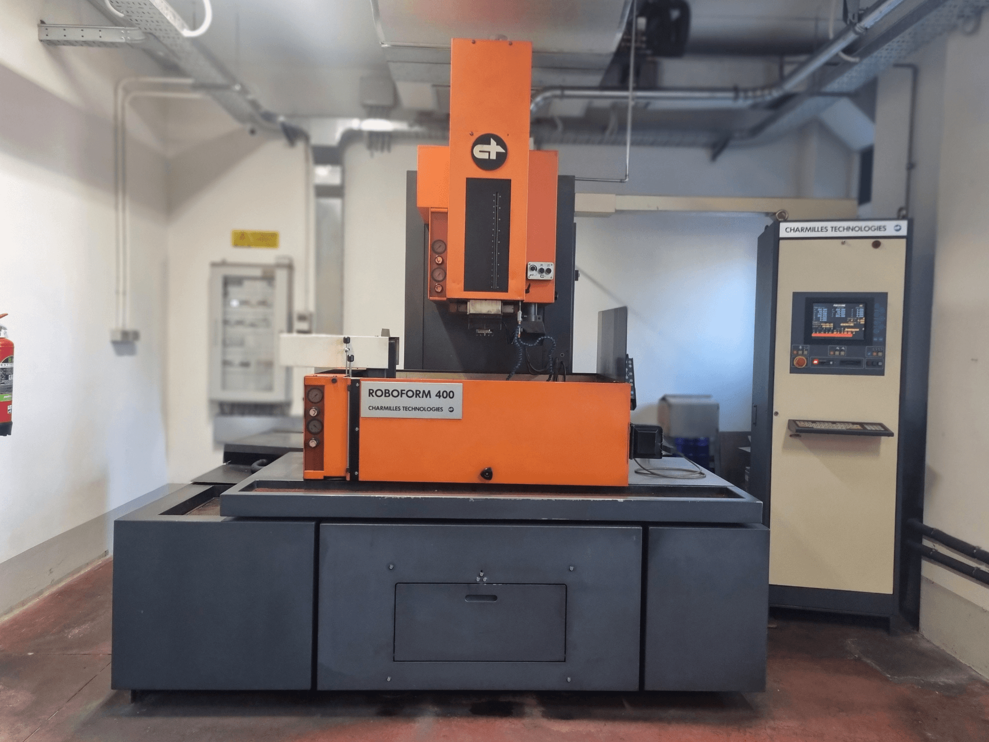 Roboforn 400 mašīna no Charmilles Technologies, skats no priekšpuses, ar oranžu un pelēku dizainu, redzams digitālais vadības panelis.