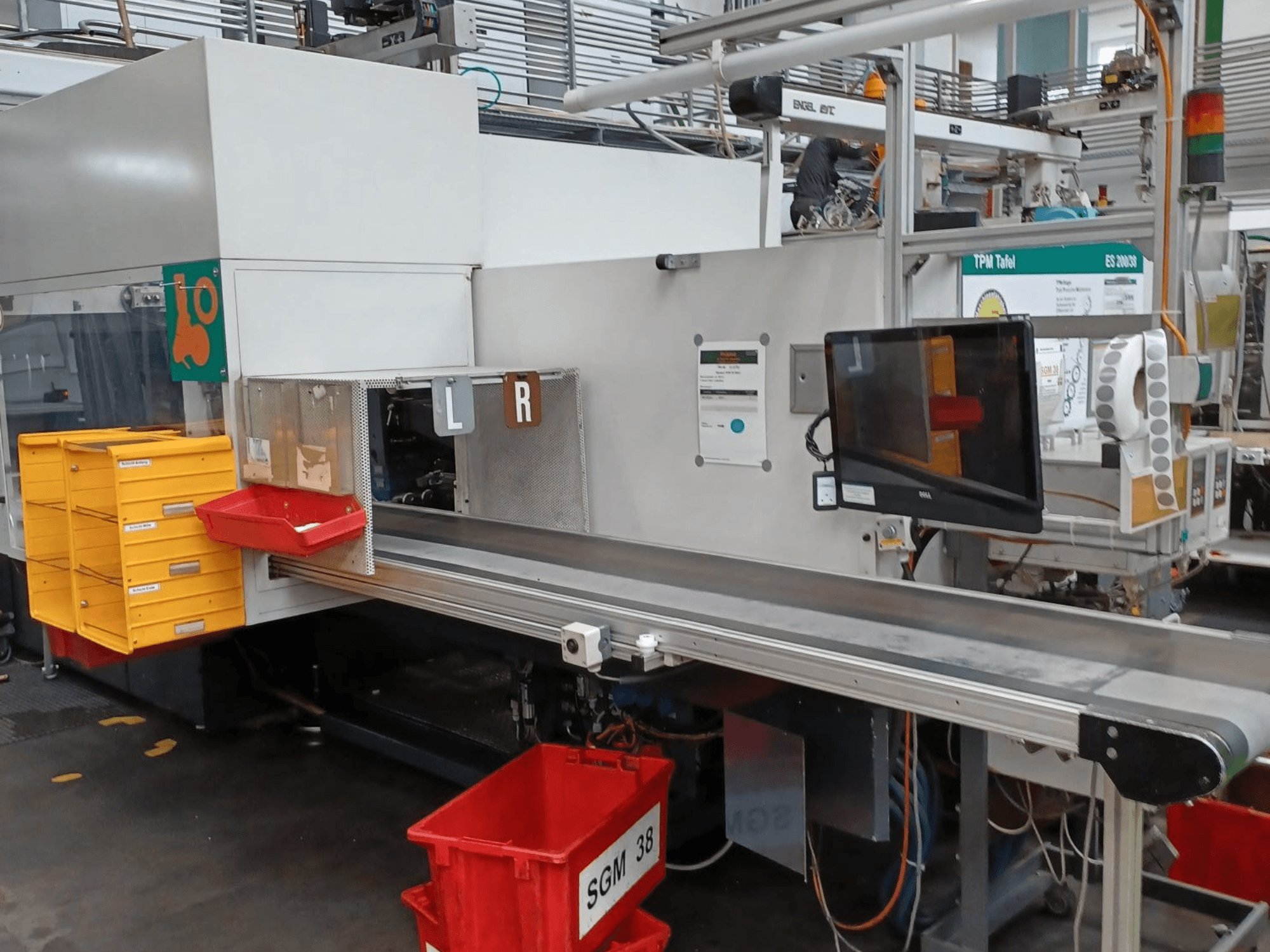 Rūpnieciskā šķirošanas iekārta ar dzeltenām un sarkanām tvertnēm, skats no sāniem, ar vadības monitoru un marķētiem šķirošanas nodalījumiem.