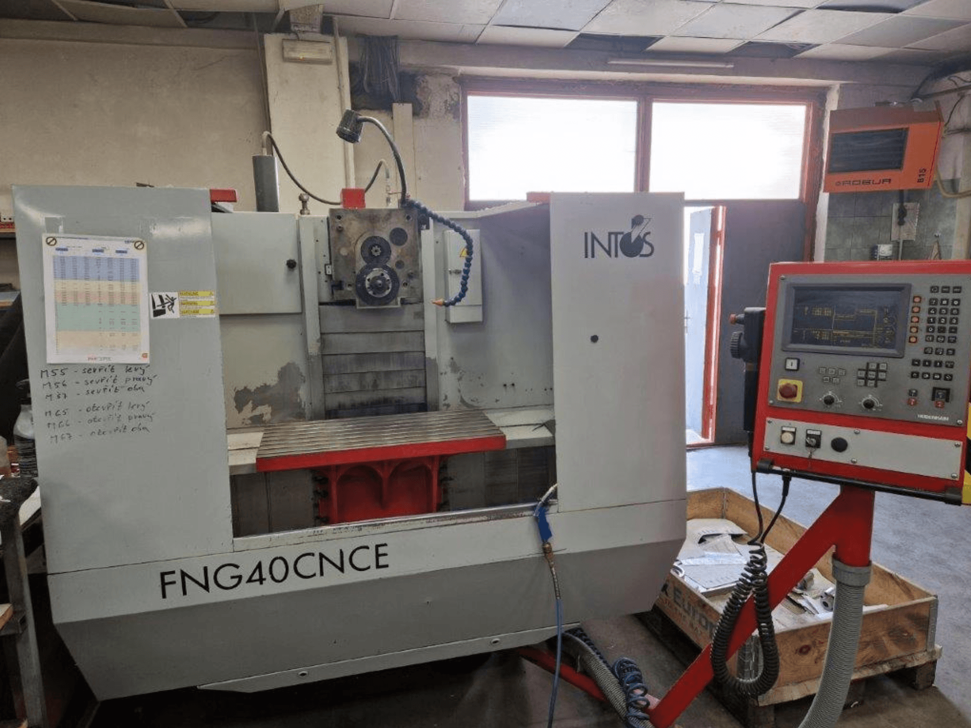 INTOS FNG40CNC mašīna, skats no priekšpuses, ar vadības paneli, darba daļām un metāla darba galdu. Ideāli piemērots apstrādei.