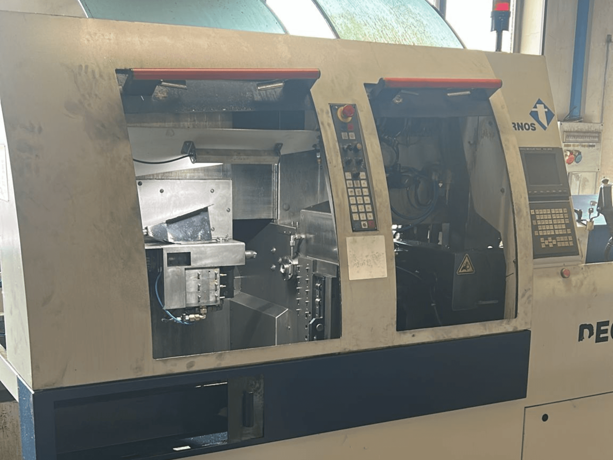 Alt teksts: b Šveices tipa virpošanas mašīnas TORNOS Deco 13 b priekšējais skats ar redzamiem vadības paneļiem un iekšējām detaļām.