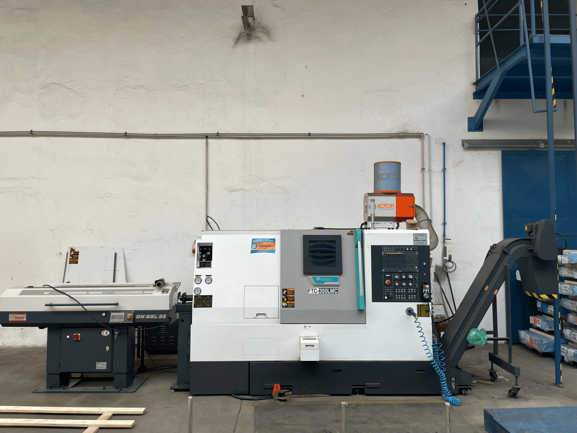 Feeler FTC 350 LMC horizontālās virpošanas mašīna darbnīcā, kurā redzams vadības panelis un instrumentu padeves līnijas. Skats no malas.
