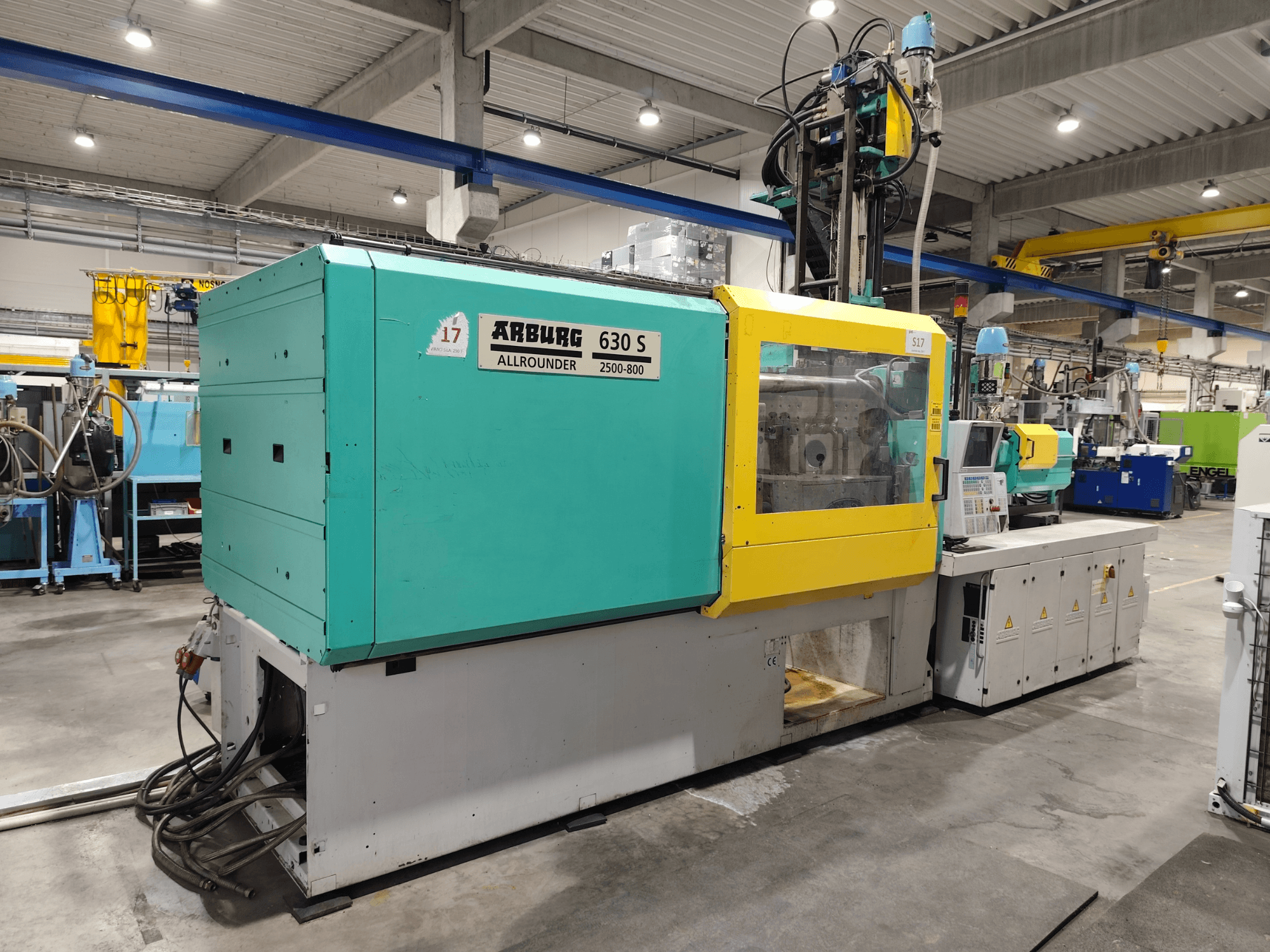 Arburg Allrounder 630S-2500-800/350 hidrauliskā plastmasas liešanas mašīna, skats no sāniem, redzama krāsaina virsma un vadības panelis.