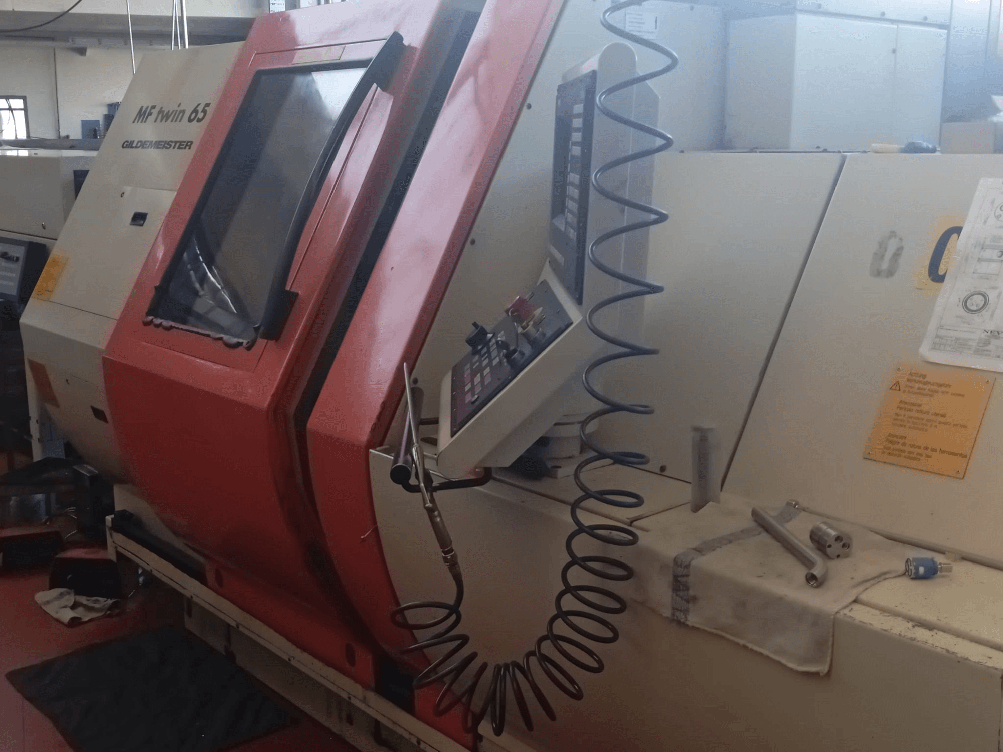 Oranži balta MF twin 65 Gliedemeister mašīna, skats no priekšpuses, ar vadības paneli un instrumentiem uz auduma.