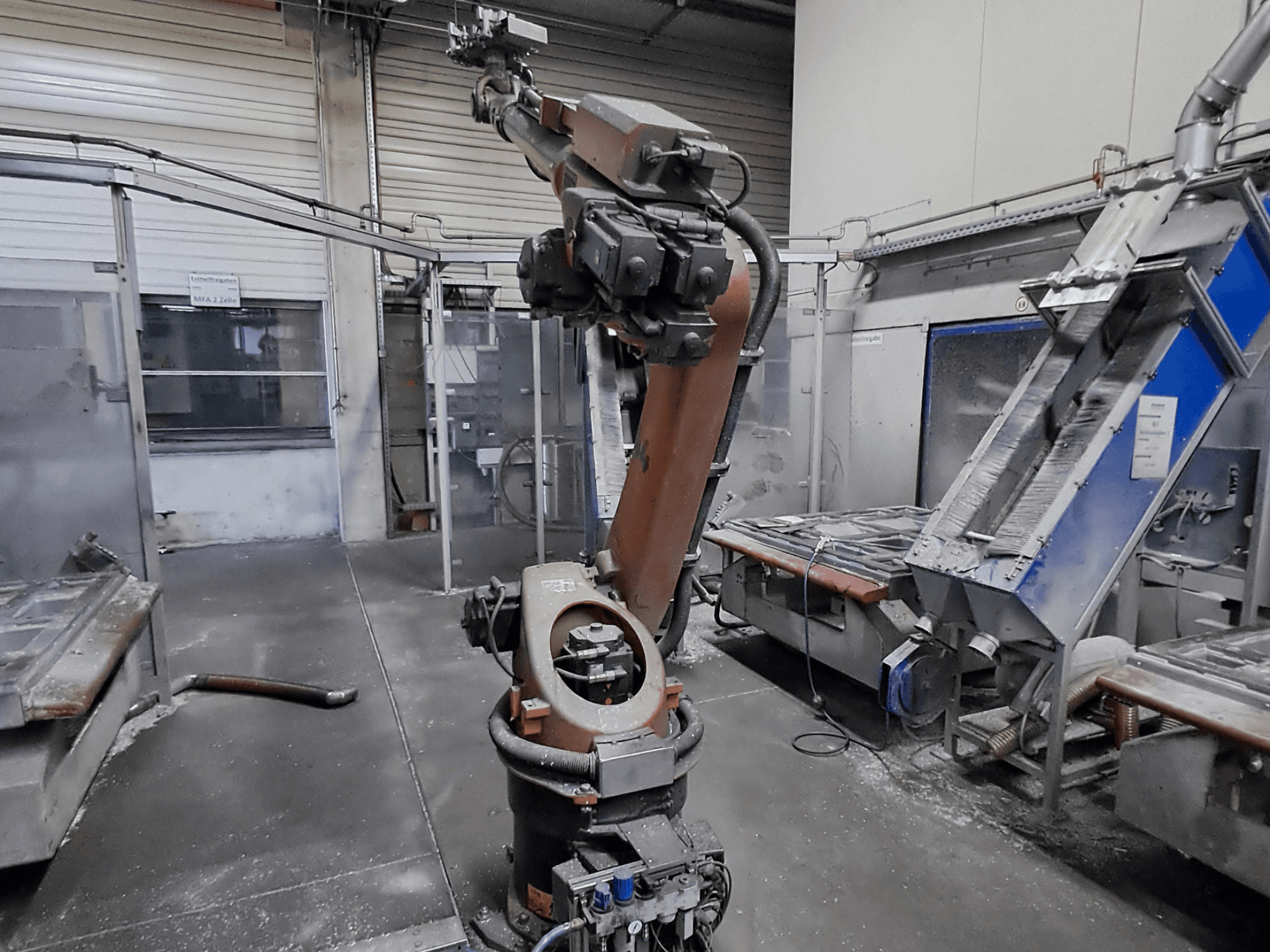 KUKA KR 30L16-2 robota roka darbnīcas vidē, skats no priekšpuses, fonā redzams putekļi un iekārtas.
