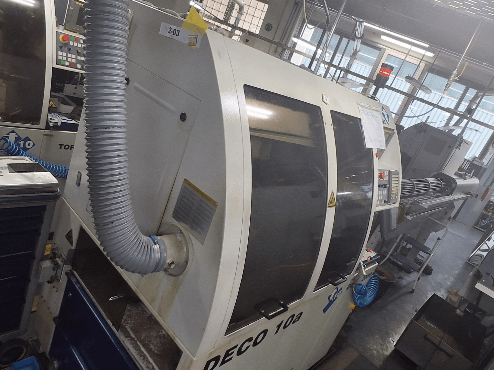 DECO 10a mašīna priekšpusē; redzams liels vadības panelis, cauruļvadi un uzlīmes.