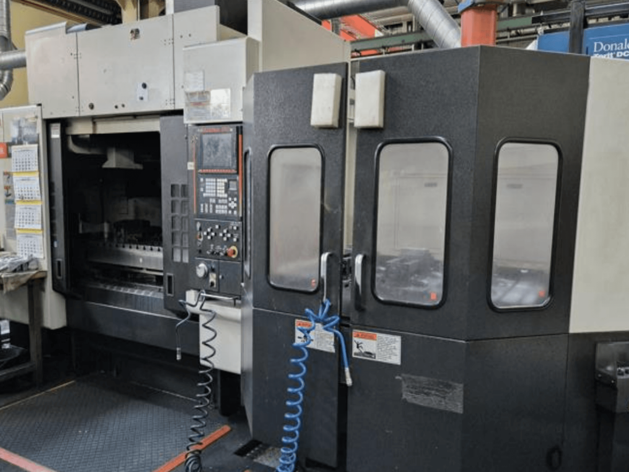 Mazak V515/40N vertikālais apstrādes centrs no priekšpuses, ar vadības paneli un slēgtu darba zonu.