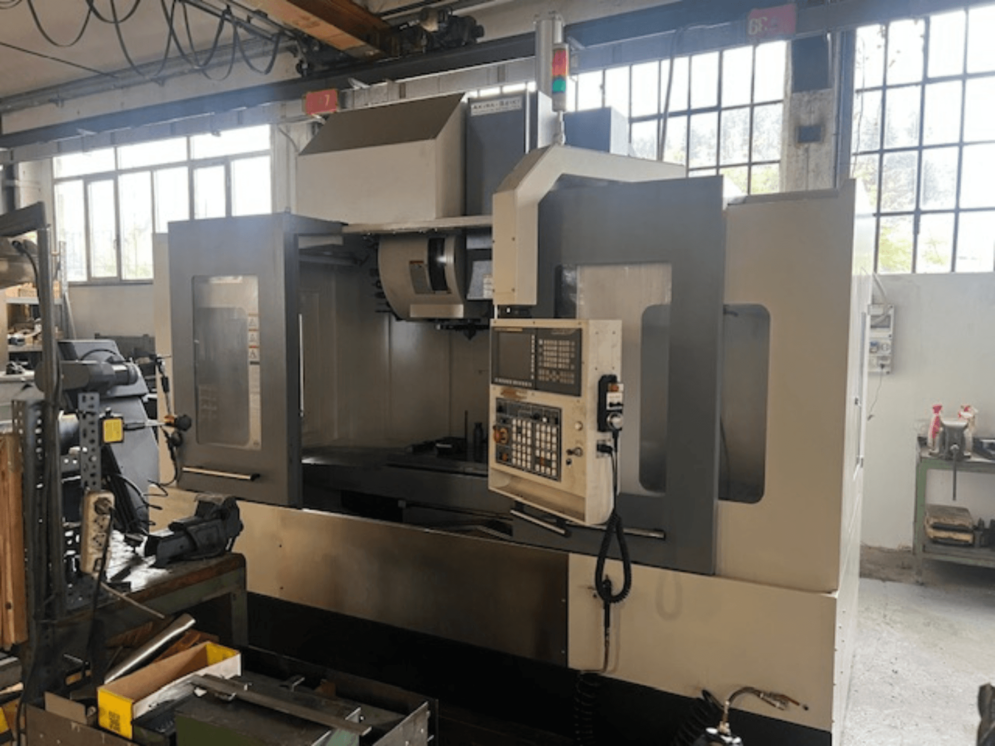 Augsto tehnoloģiju CNC frēzmašīna, skats no priekšpuses, ar digitālo vadību, pamata drošības indikatoriem un kompaktu dizainu.