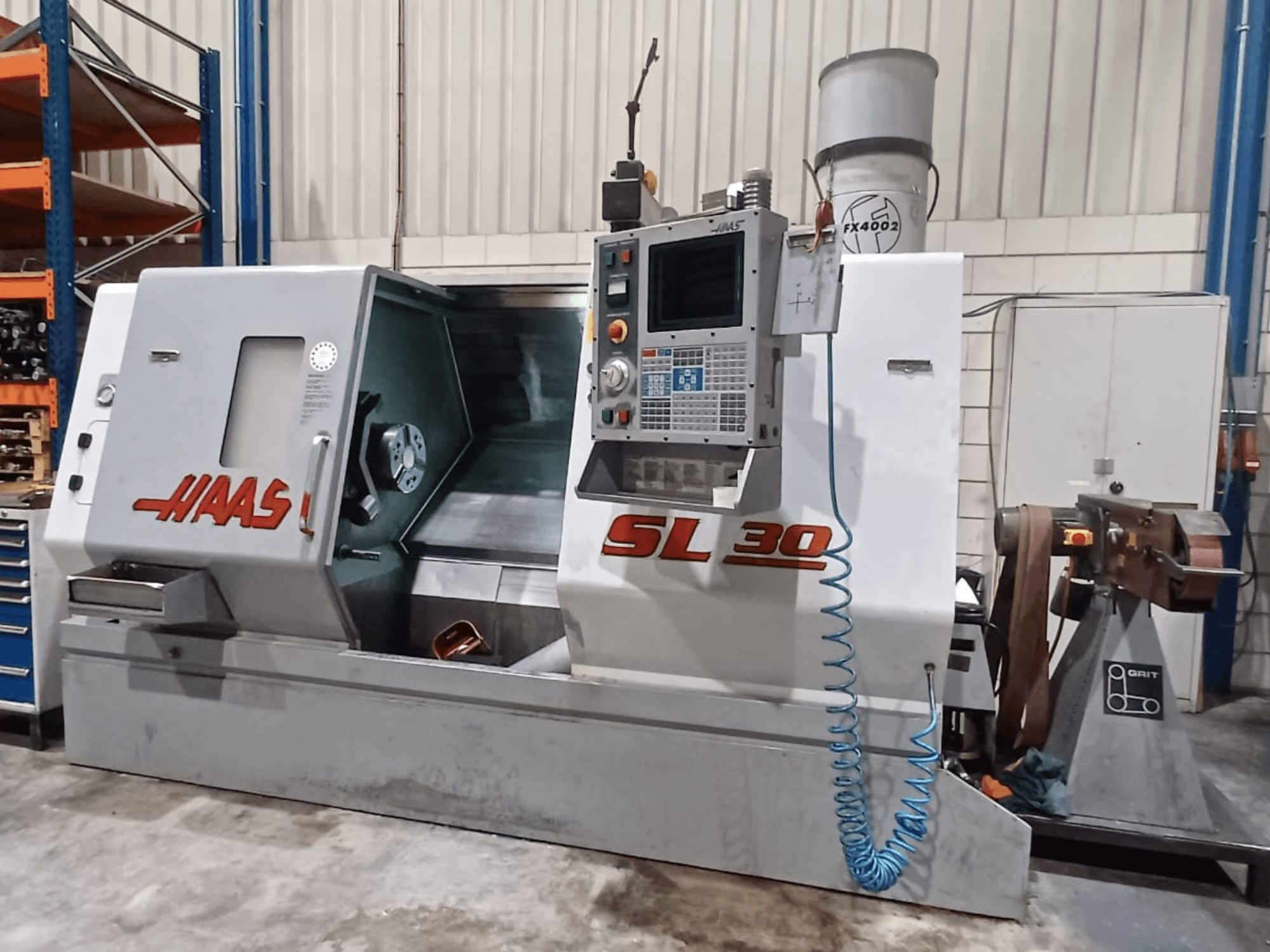 Haas SL 30 CNC virpa sānskatā, kurā redzams vadības panelis, apstrādes zona un metālapstrādei integrētā dzesēšanas šķidruma sistēma.