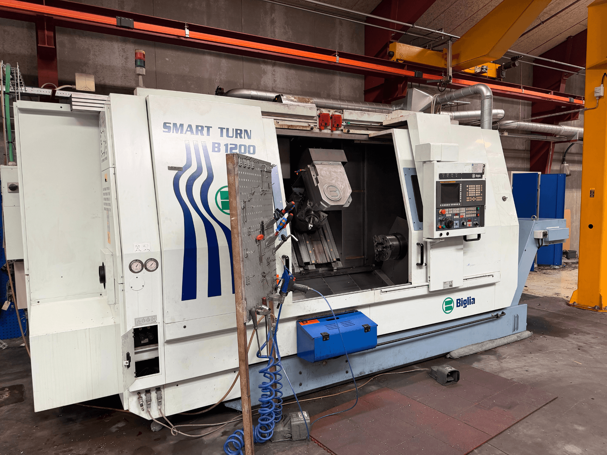 Biglia B.1200/S-Smart virpošanas un frēzēšanas centrs, skats no priekšpuses; redzamas vadības ierīces, detaļa vārpstā un spiediena mērītāji.