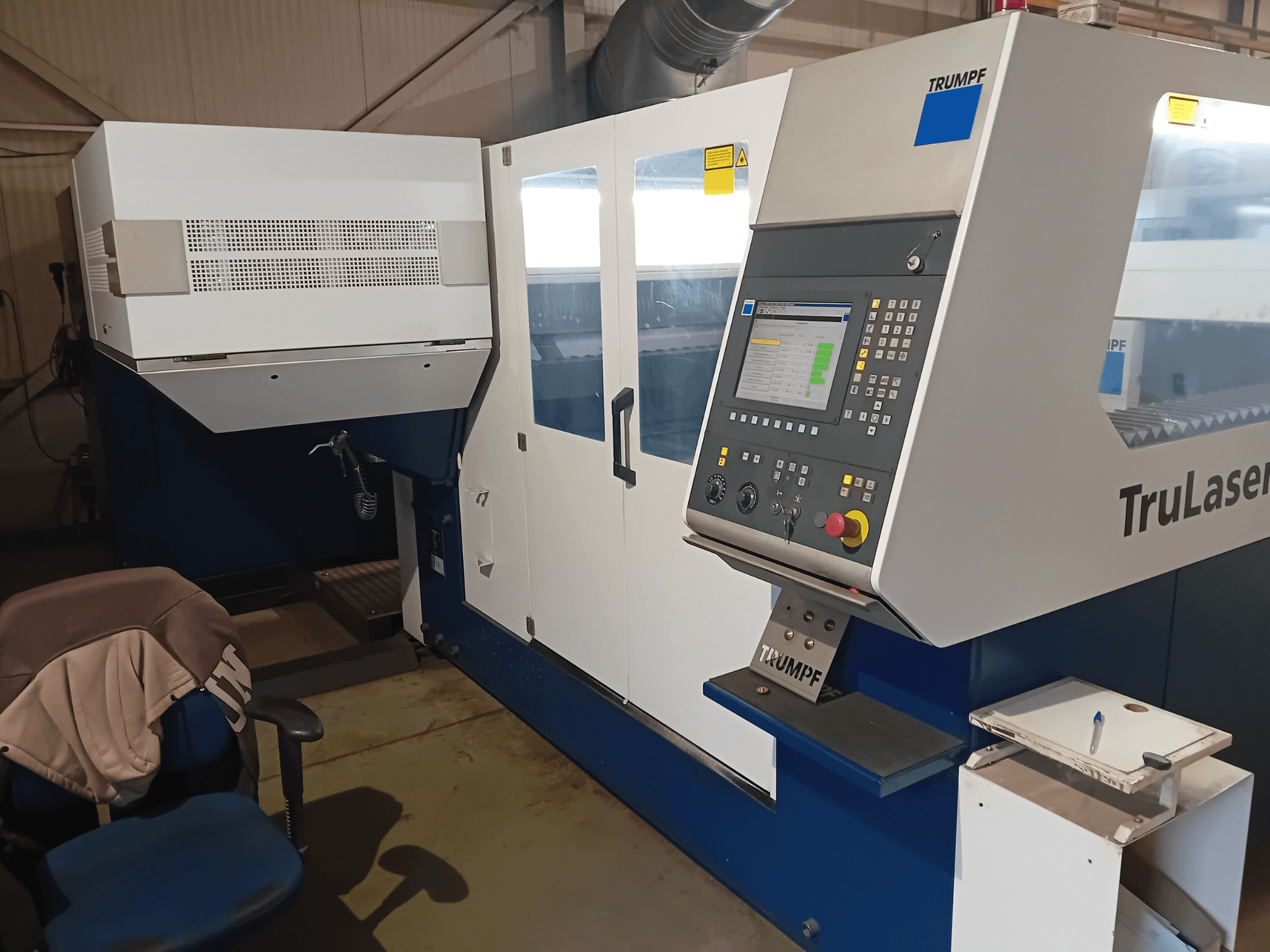 TRUMPF TruLaser 3030 CO2 lāzera griešanas iekārta, priekšējais skats, redzams vadības panelis un operatora stacija.