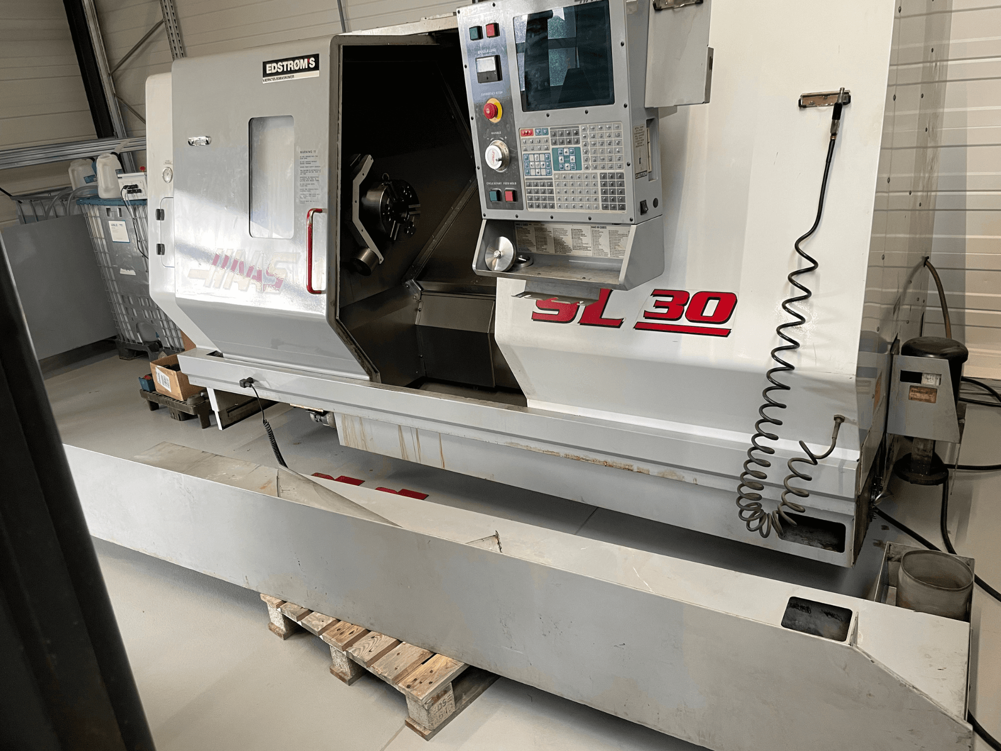 Haas SL 30 CNC virpas darbnīcā, skats no sāniem, ar vadības paneli un atvērtu vārpstu apstrādes darbiem.