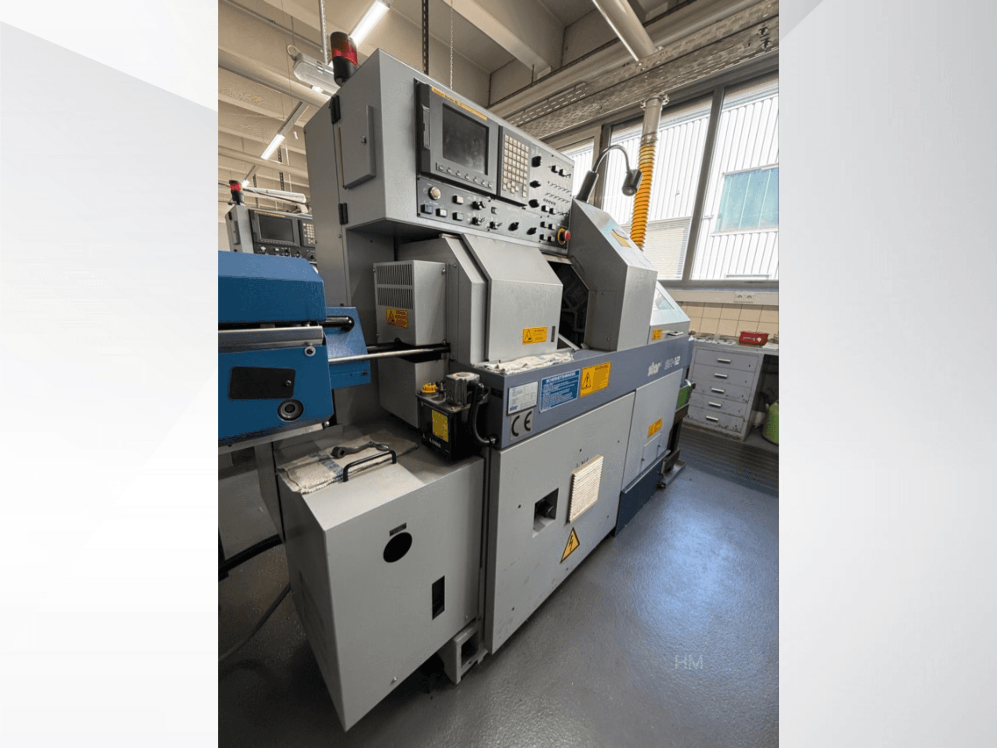 Lithec 3231 mašīnas priekšējais skats, kurā redzams vadības panelis, motors un zilā padeves sekcija labi apgaismotā rūpnieciskā vidē.