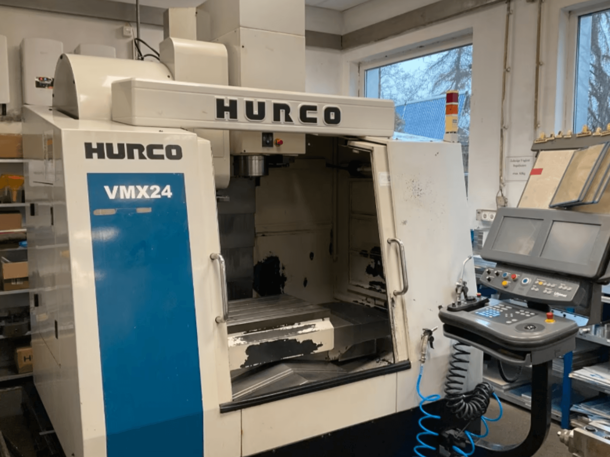 Hurco VMX24 vertikālais apstrādes centrs, skats no priekšpuses, kurā redzams vadības panelis, vārpstas galva un darba zona, ar nelielām nolietojuma pazīmēm.
