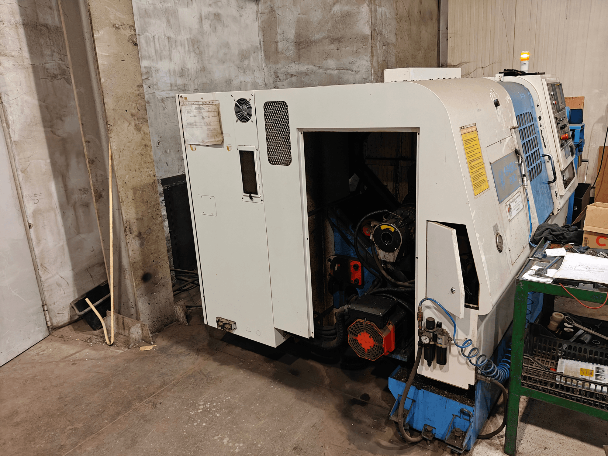 Virpmašīnas priekšējais skats, zīmols un modelis nav norādīts, ar vadības ierīcēm un redzamām motora sastāvdaļām.