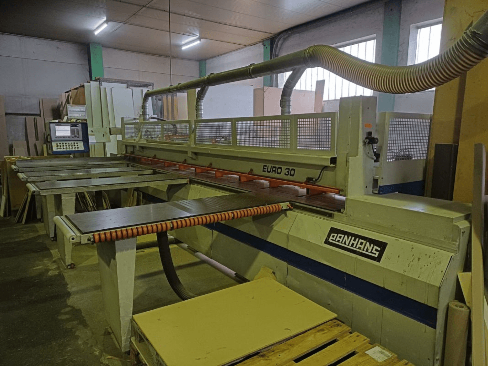 PANHANS EURO 30 paneļu zāģa priekšējais skats ar vadības paneli, griešanas galdu un putekļu nosūces šļūteni darbnīcā.