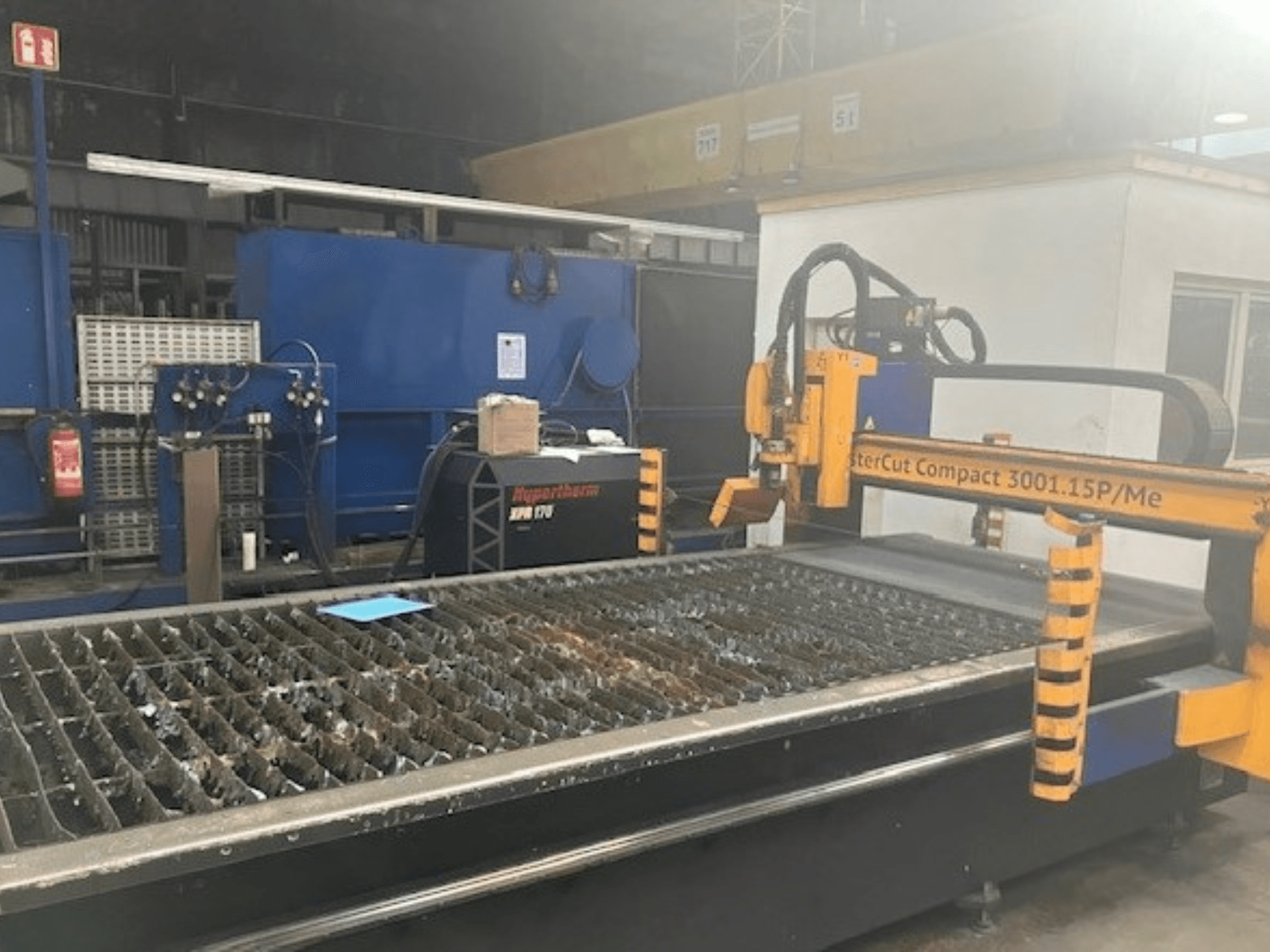 Hypertherm MasterCut Compact 3001.15P/Me plazmas griešanas iekārta sānu skatā, redzams griešanas galds un vadības panelis.