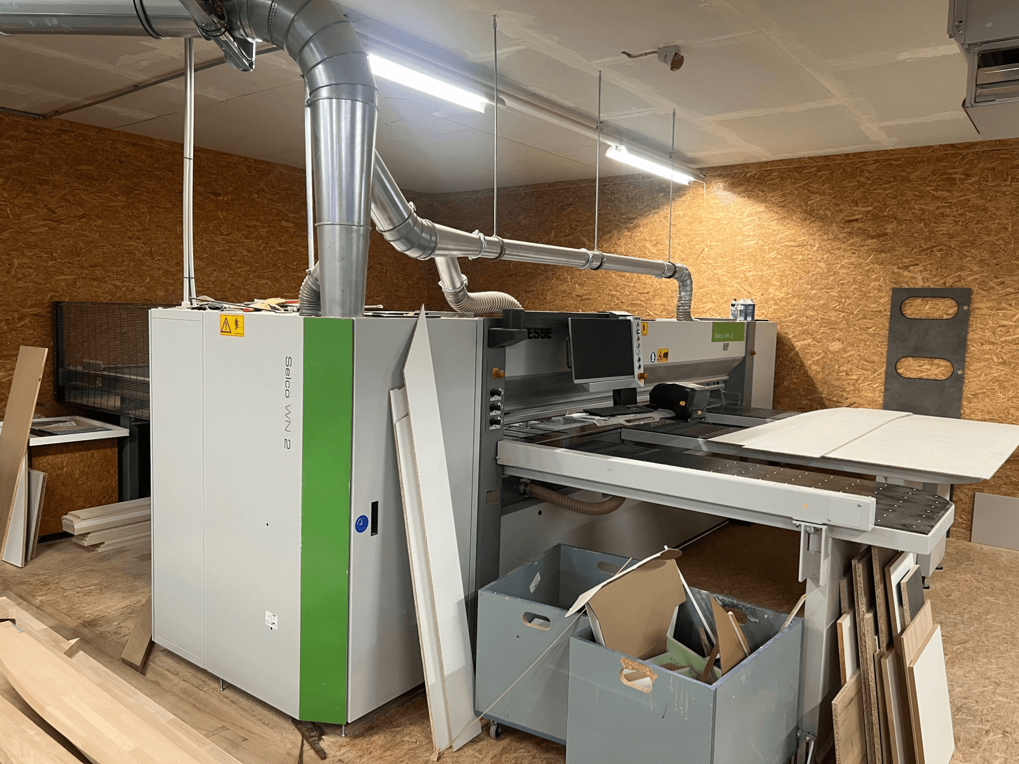 BIESSE Selco WN 2 paneļu zāģis darbnīcā, ar lielu griešanas galdu un putekļu nosūces sistēmu, skats no sāniem.