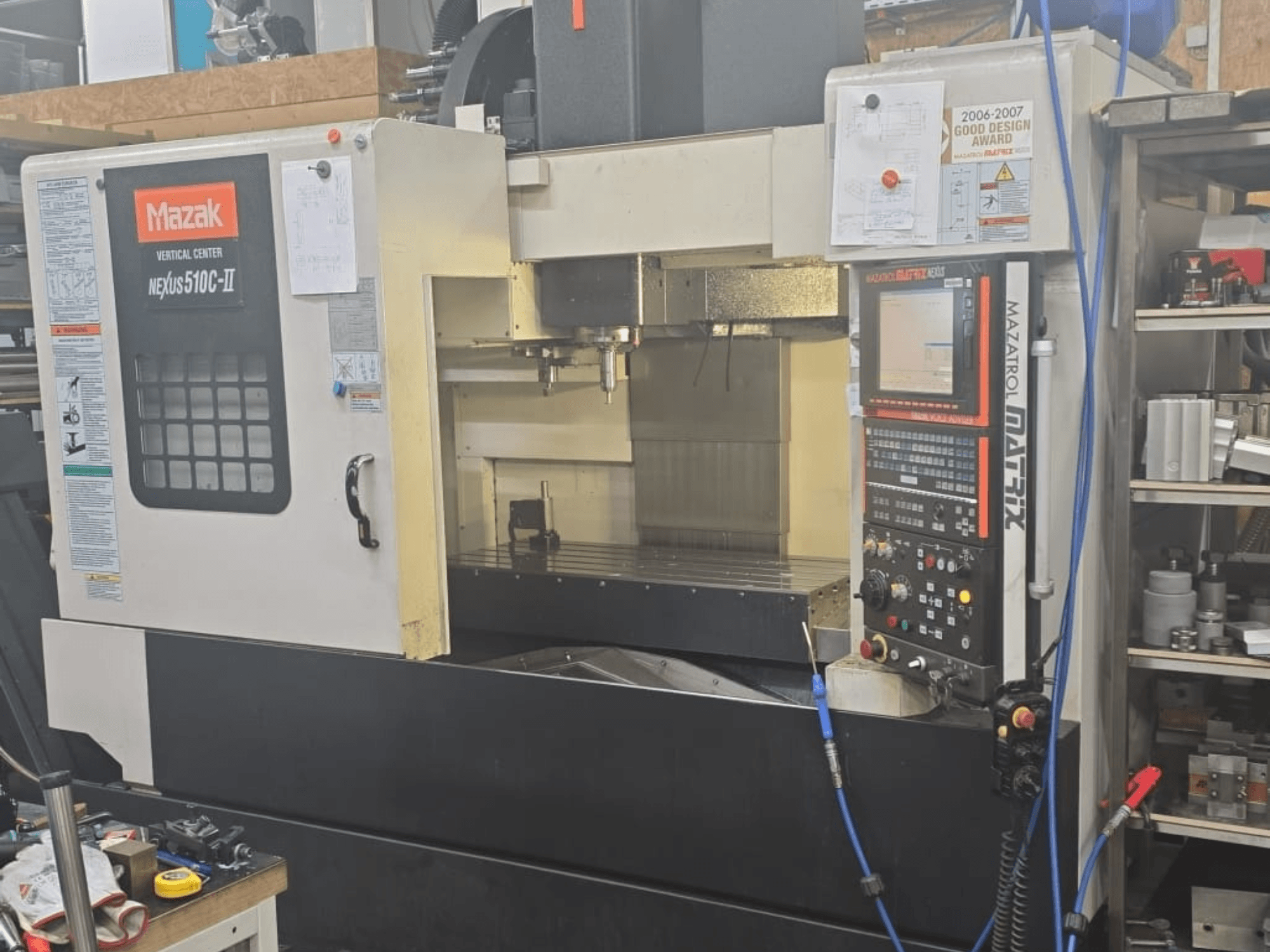Mazak VERTIKĀLAIS CENTRS NEXUS 510C-II, priekšējais skats, kurā redzams vadības panelis, apstrādes zona un darbības funkcijas.